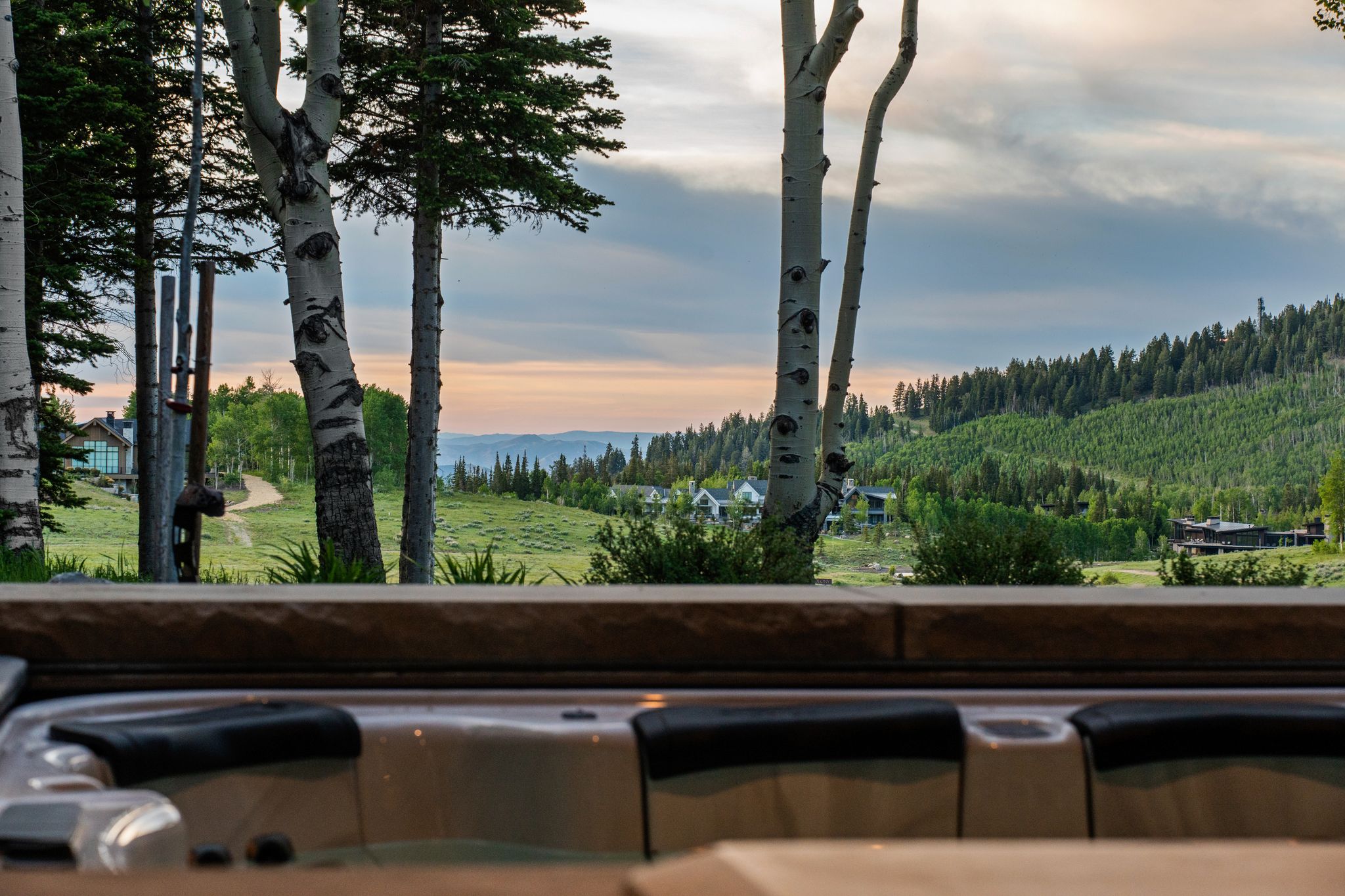 Outdoor spa with integrated seating, surrounded by mature trees