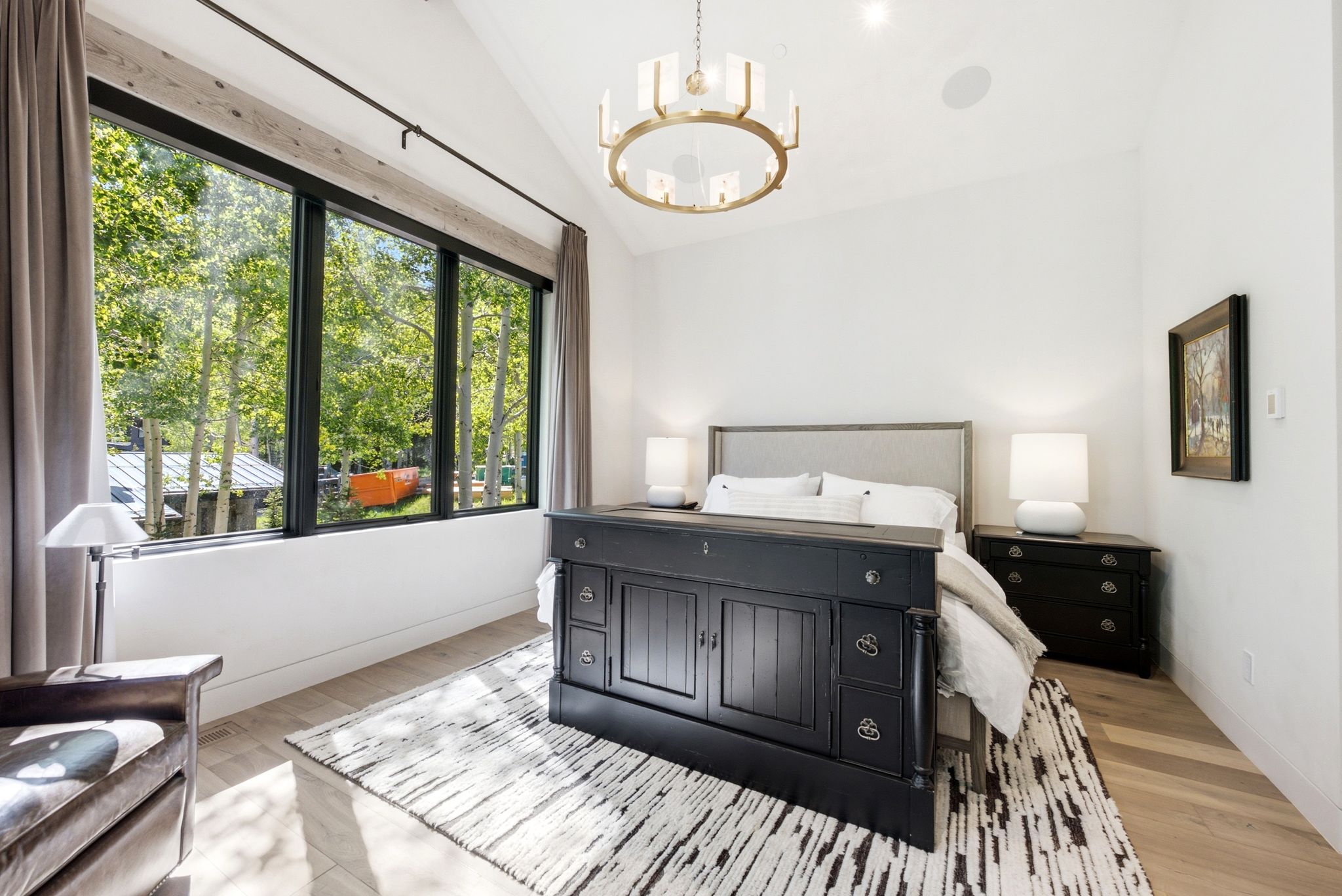 Expansive windows with black framing, wood-finish flooring, a vaulted ceiling, a contemporary chandelier, and recessed lighting