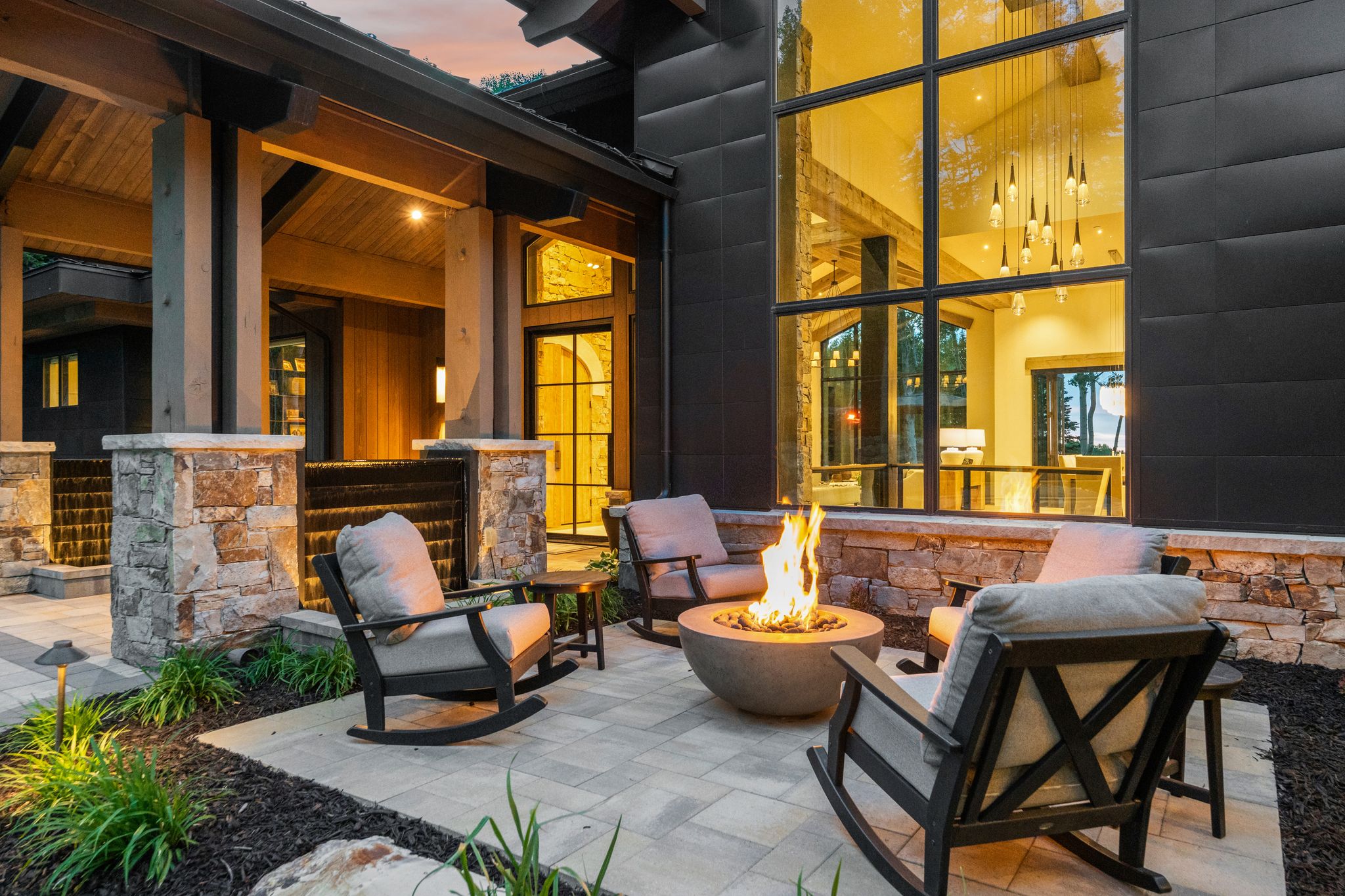 Outdoor patio featuring paver flooring, a built-in stone fire pit, and stone retaining walls