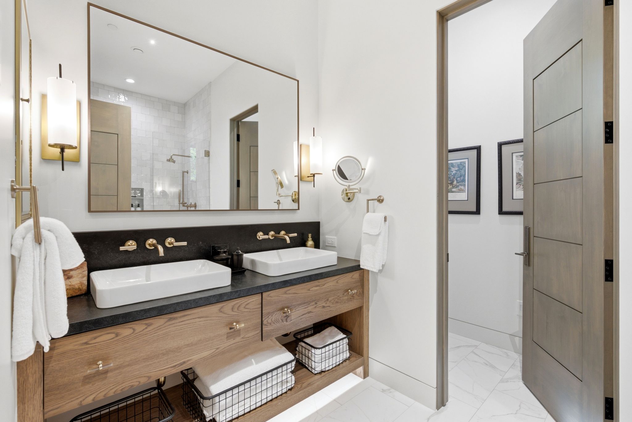 Double vanity with a dark countertop, two rectangular vessel sinks, and wall-mounted brass faucets