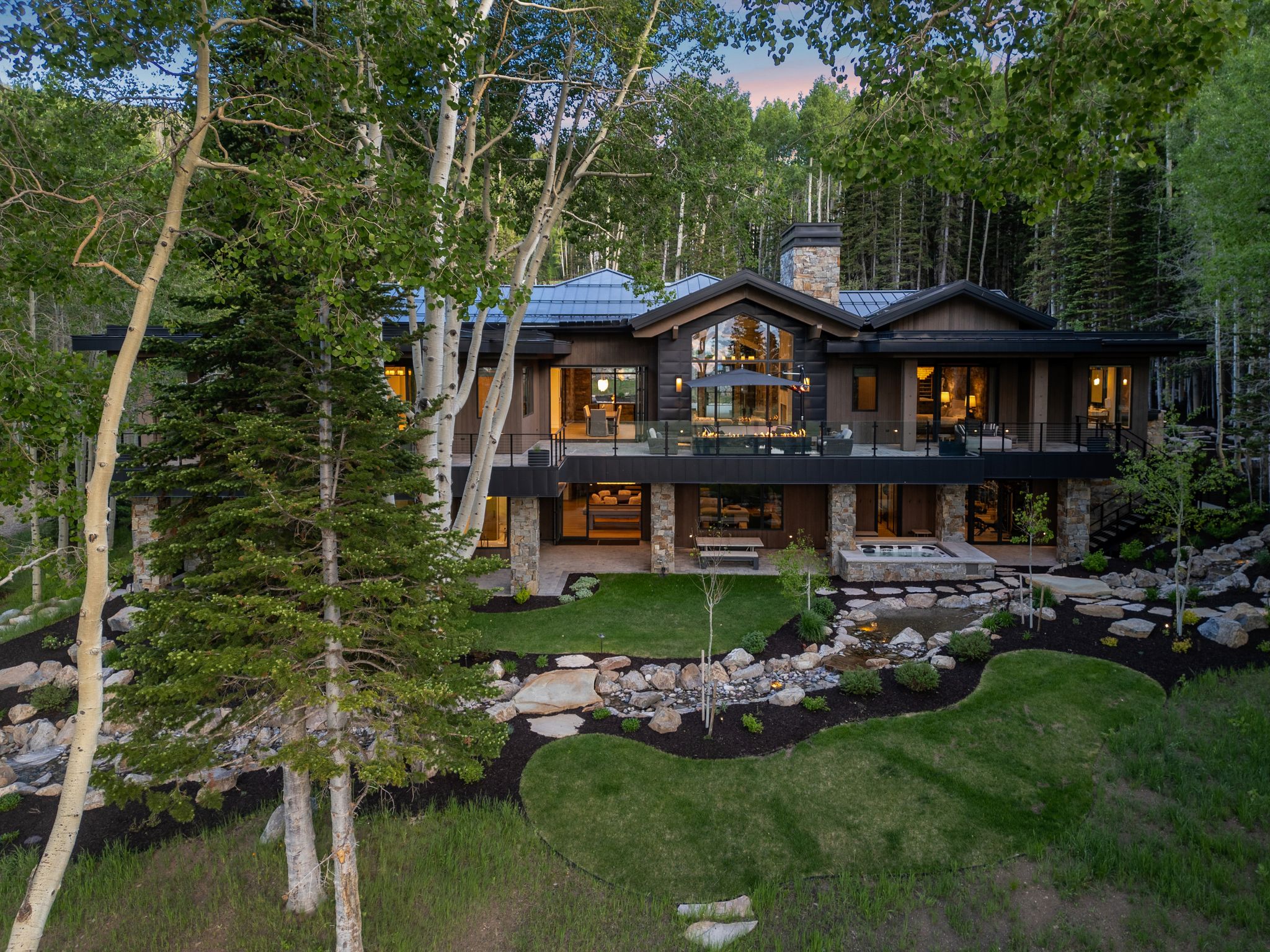 Multi-level residence featuring extensive glass railing balconies and dark-stained wood siding with stone accents