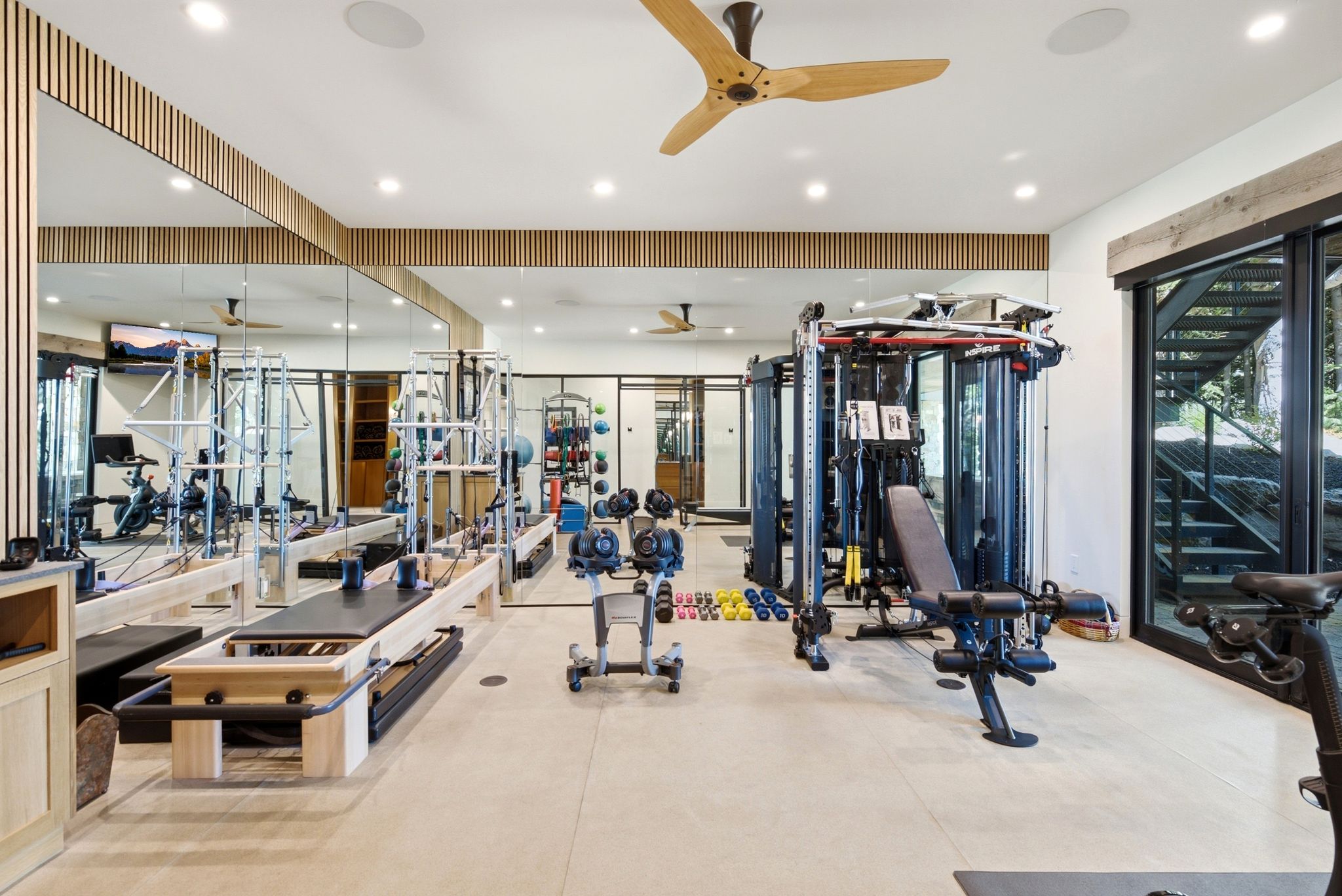 Dedicated fitness room featuring light-toned flooring, full-wall mirrored panels, and recessed lighting