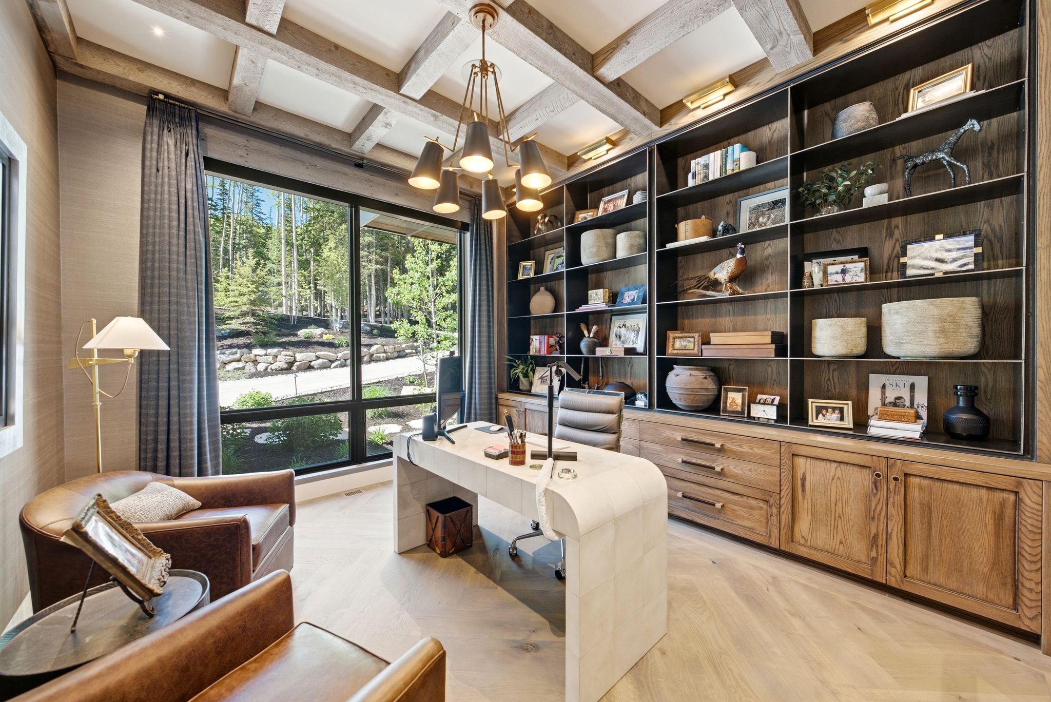 Spacious room featuring exposed ceiling beams, a striking chandelier, custom built-in shelving with integrated cabinetry, and wood-finish flooring