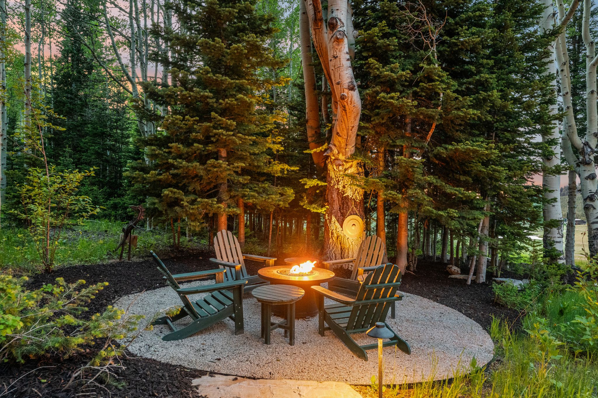 Outdoor fire pit area featuring a circular gravel patio and surrounding mulch