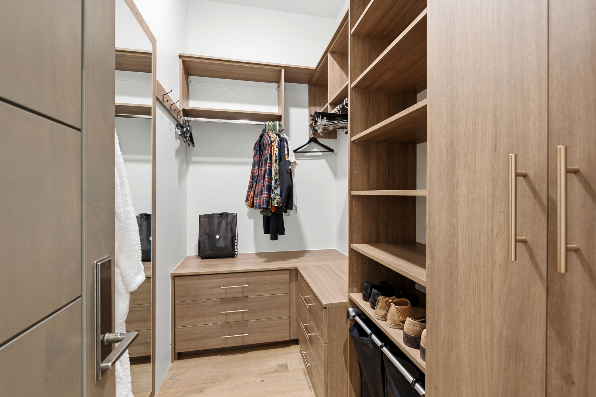Custom closet system featuring wood-finish cabinetry, extensive shelving, drawer storage, and integrated hanging rods