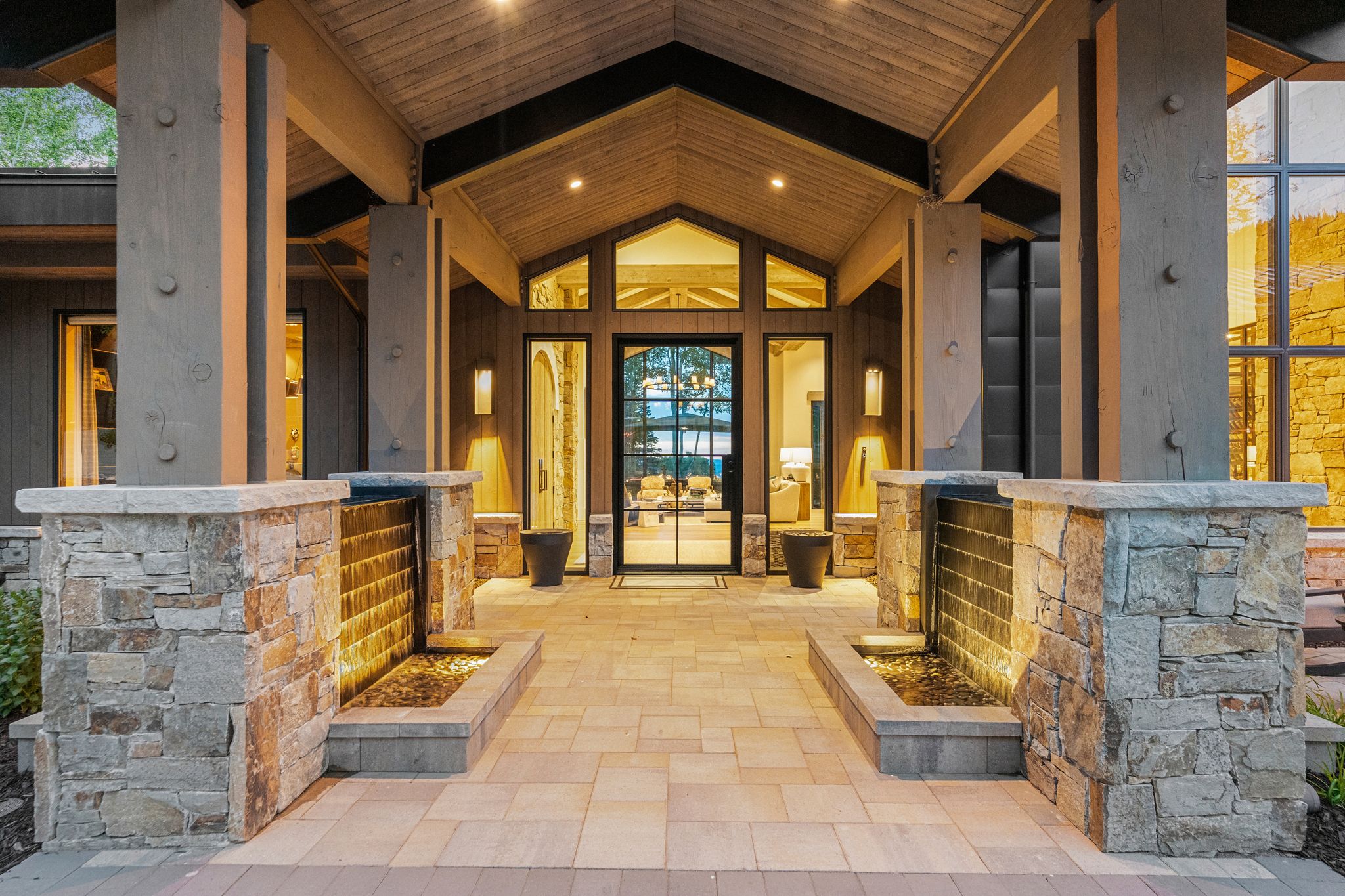 Expansive covered entry featuring a vaulted wood ceiling, substantial exposed beams, and a paver walkway
