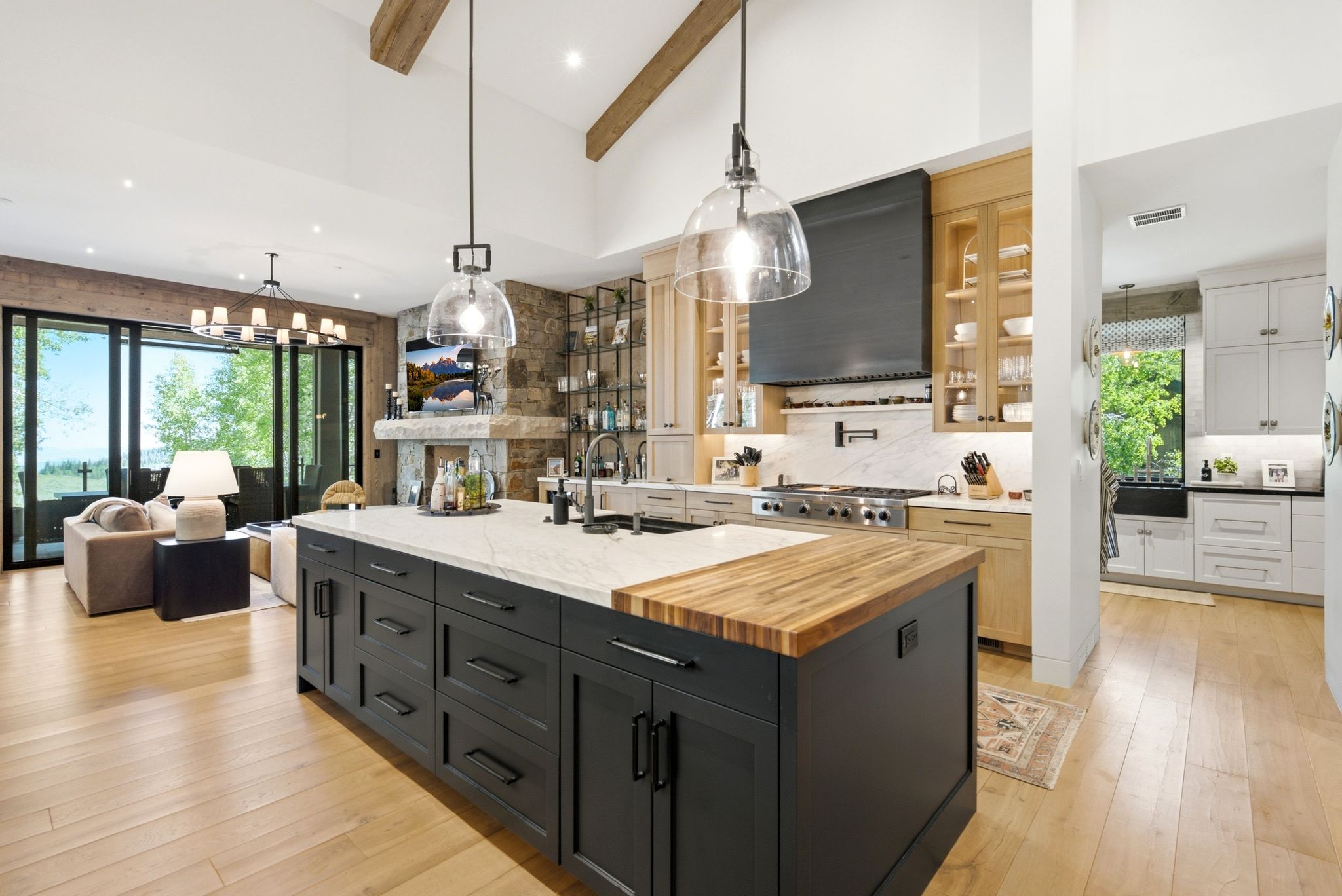 Spacious kitchen featuring a large island with a butcher block counter extension, dark cabinetry, and two pendant lights