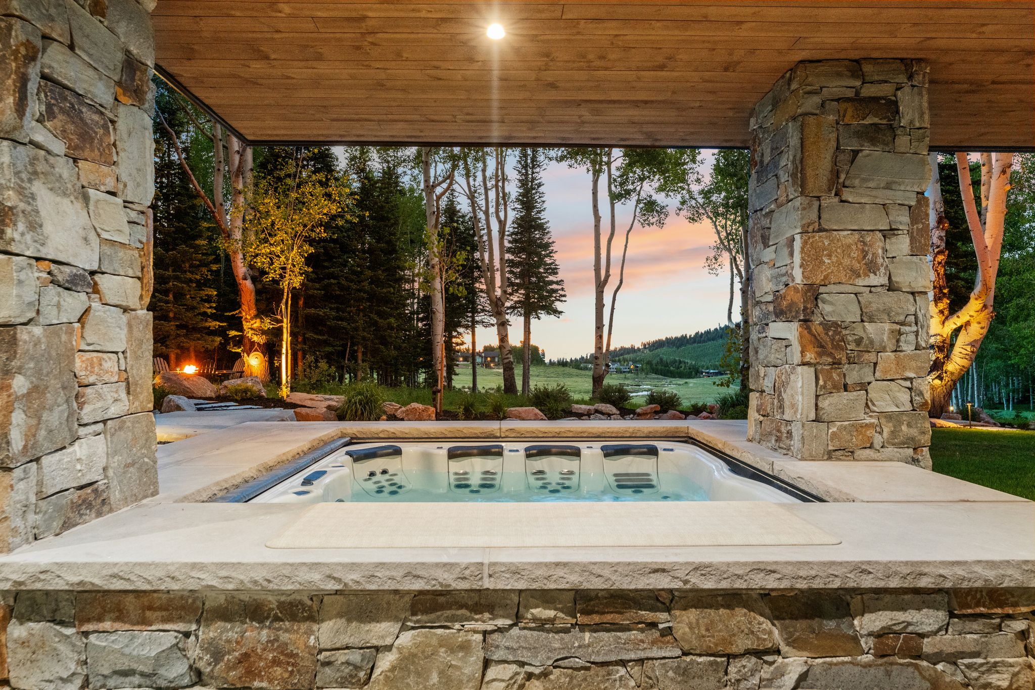 Built-in spa featuring a stone surround and concrete decking, all under a wood-paneled ceiling