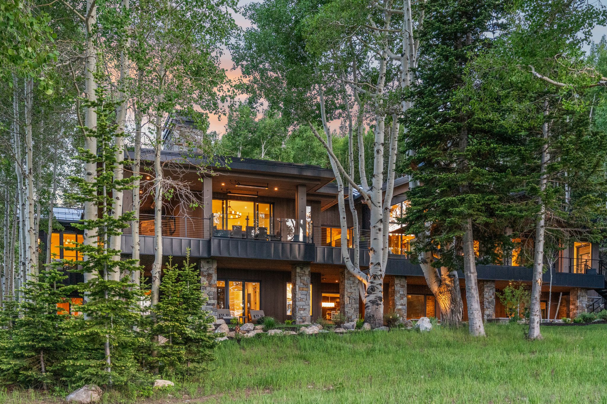 Modern multi-level residence featuring extensive natural stone accents and dark-paneled siding
