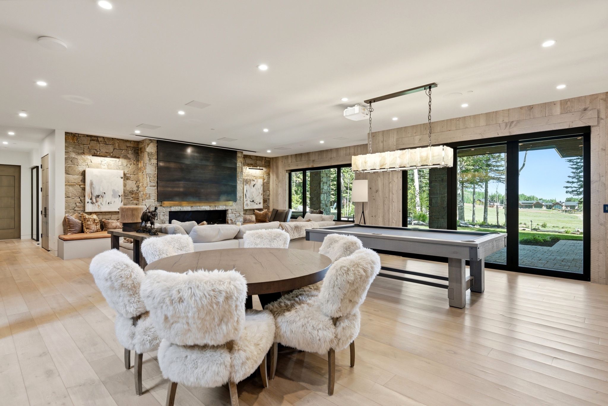 Spacious living area featuring light wood-finish flooring and a stone accent wall with a fireplace