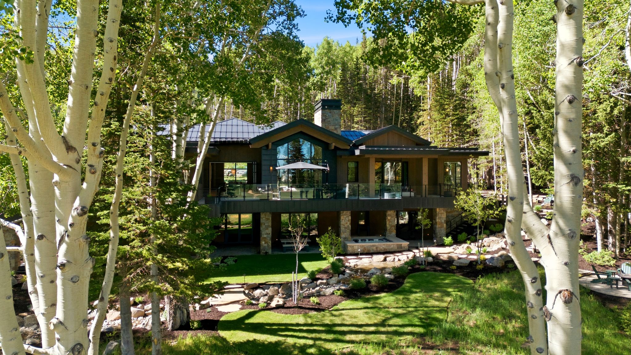 Multi-level contemporary residence featuring extensive glass panels and a dark metal roof
