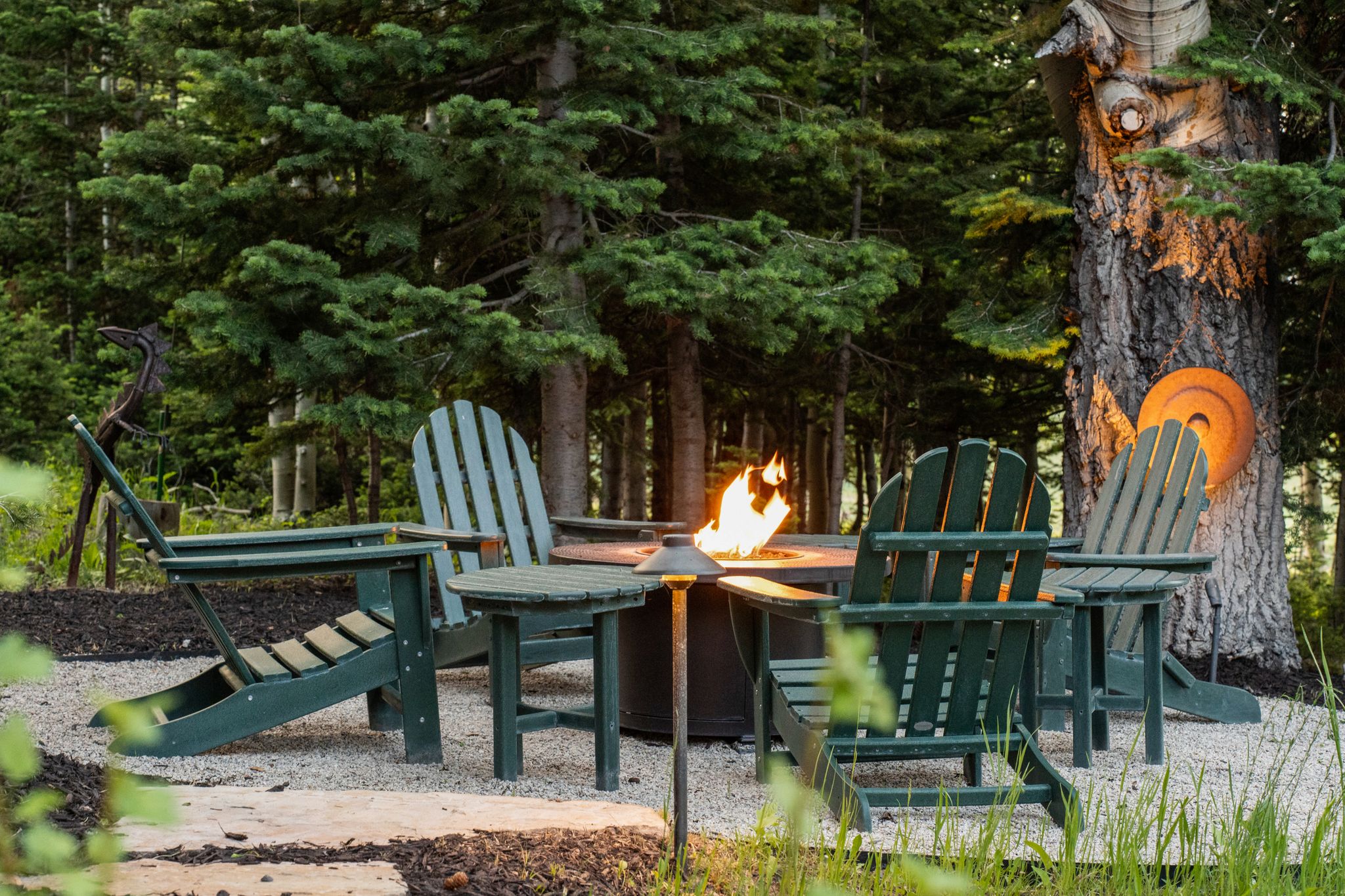 Outdoor fire pit area with gravel hardscaping surrounded by mature trees