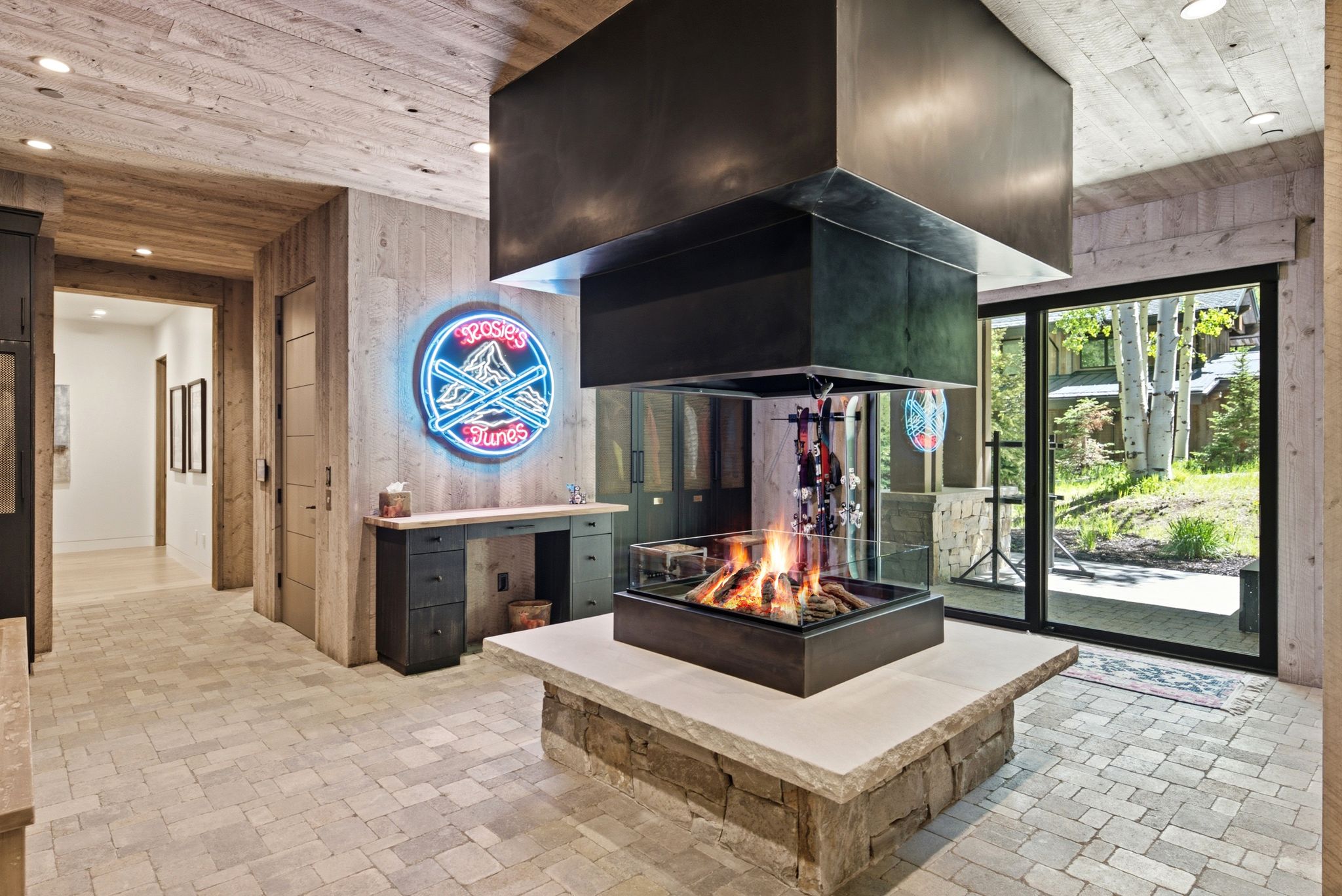 Central fireplace featuring a glass enclosure and suspended metal hood