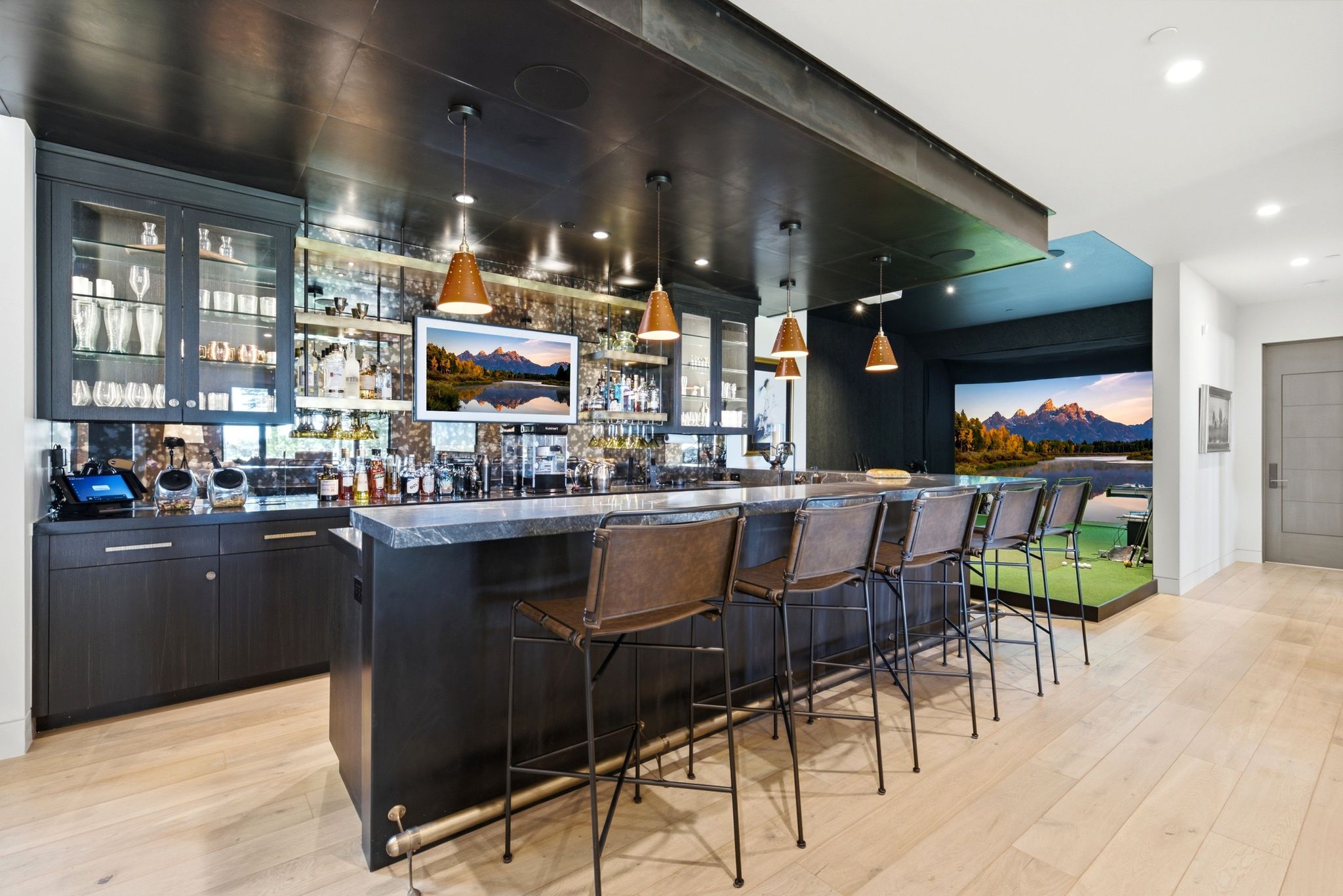 Custom bar area featuring a stone countertop, dark cabinetry, and multiple pendant lights