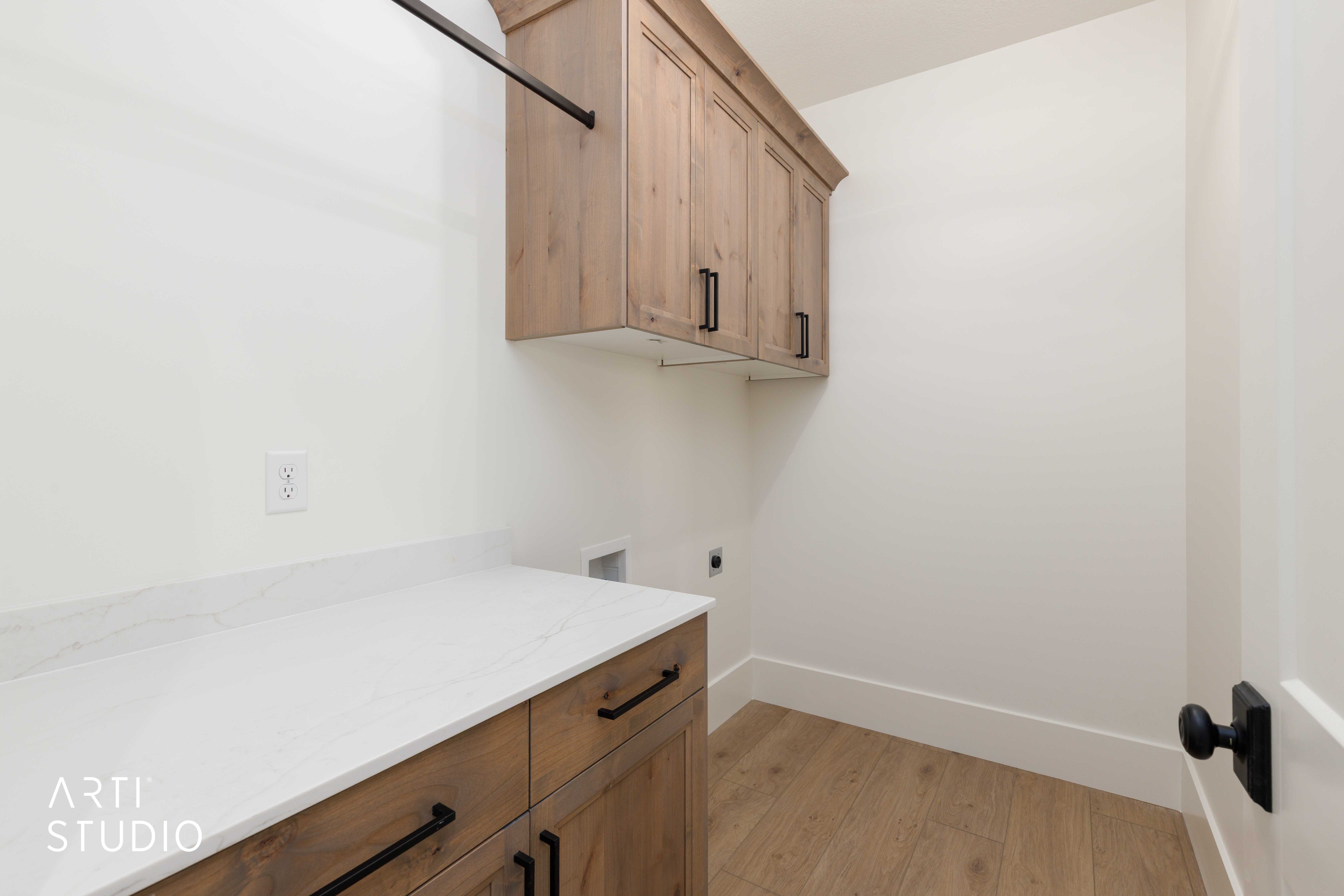 Laundry area featuring wood-finish flooring, white walls, and a quartz countertop