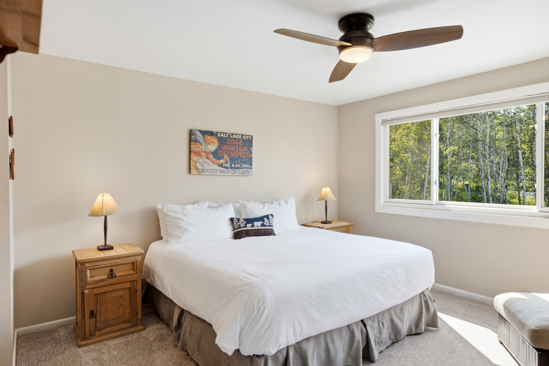 Bedroom featuring a large window, a ceiling fan with integrated lighting, and neutral tone carpeting