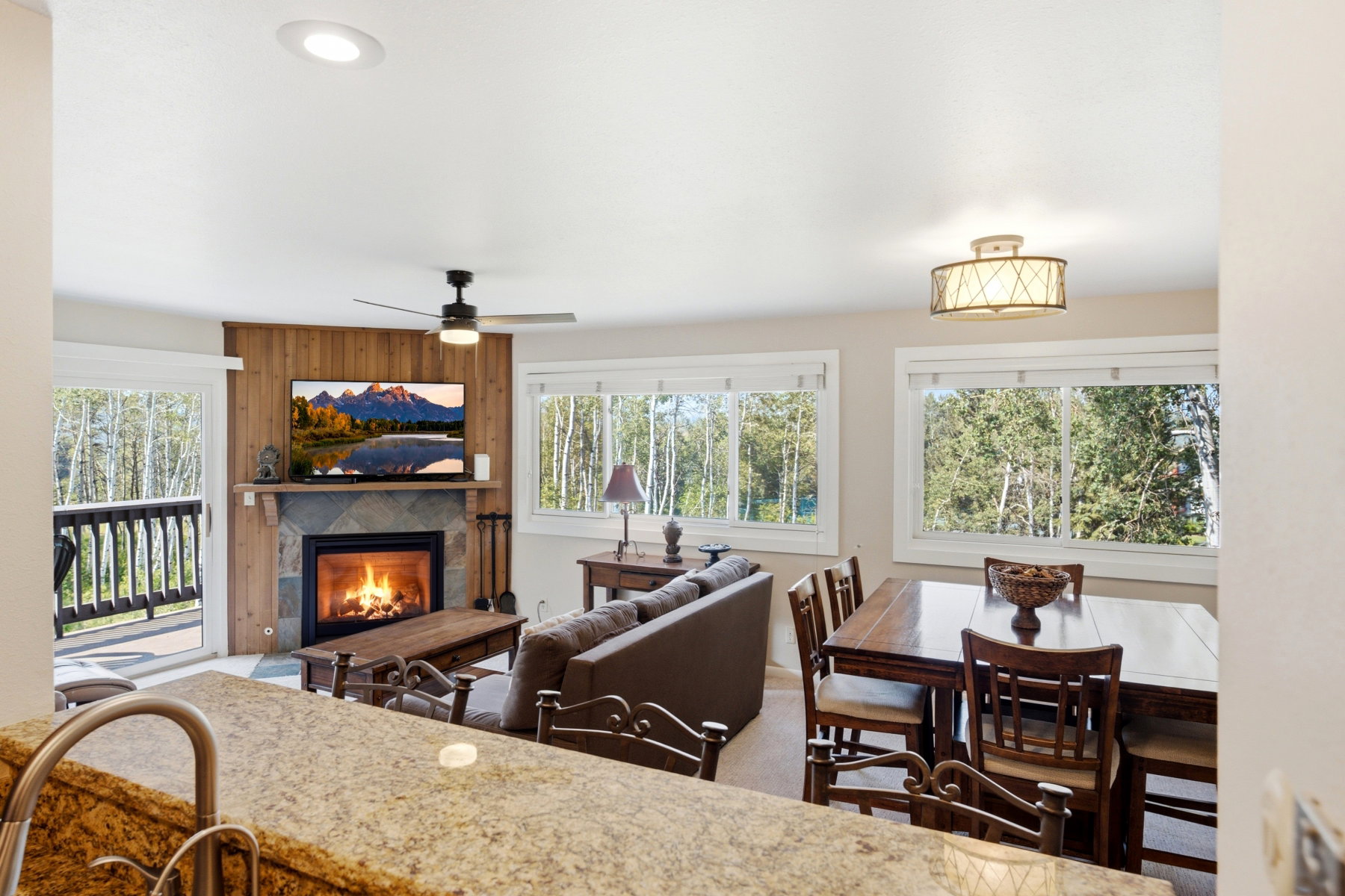 Living area featuring a stone-faced fireplace with a wood mantel, wood paneling, and an adjacent sliding glass door to a balcony