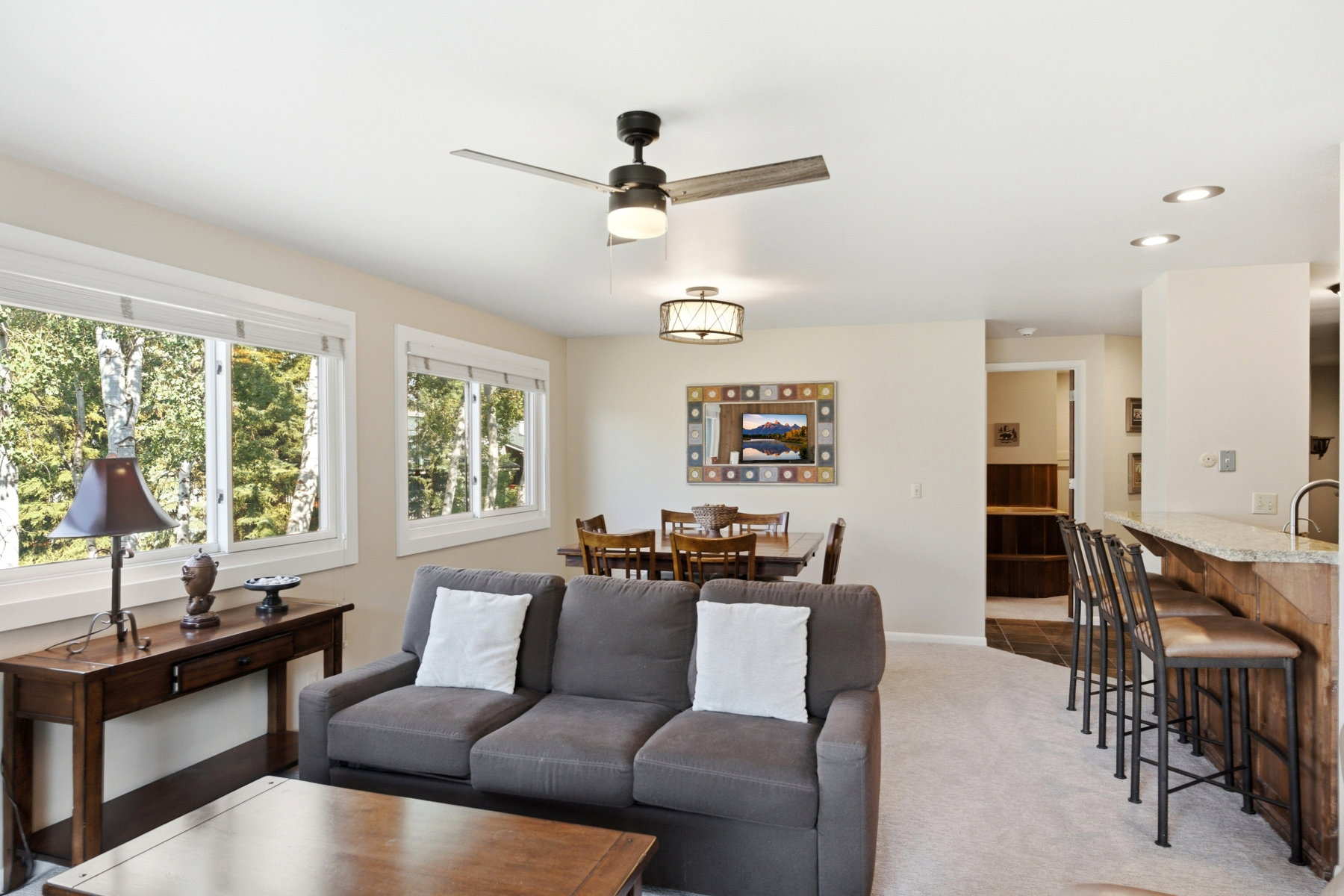 Open-concept living area featuring light neutral walls and carpet flooring