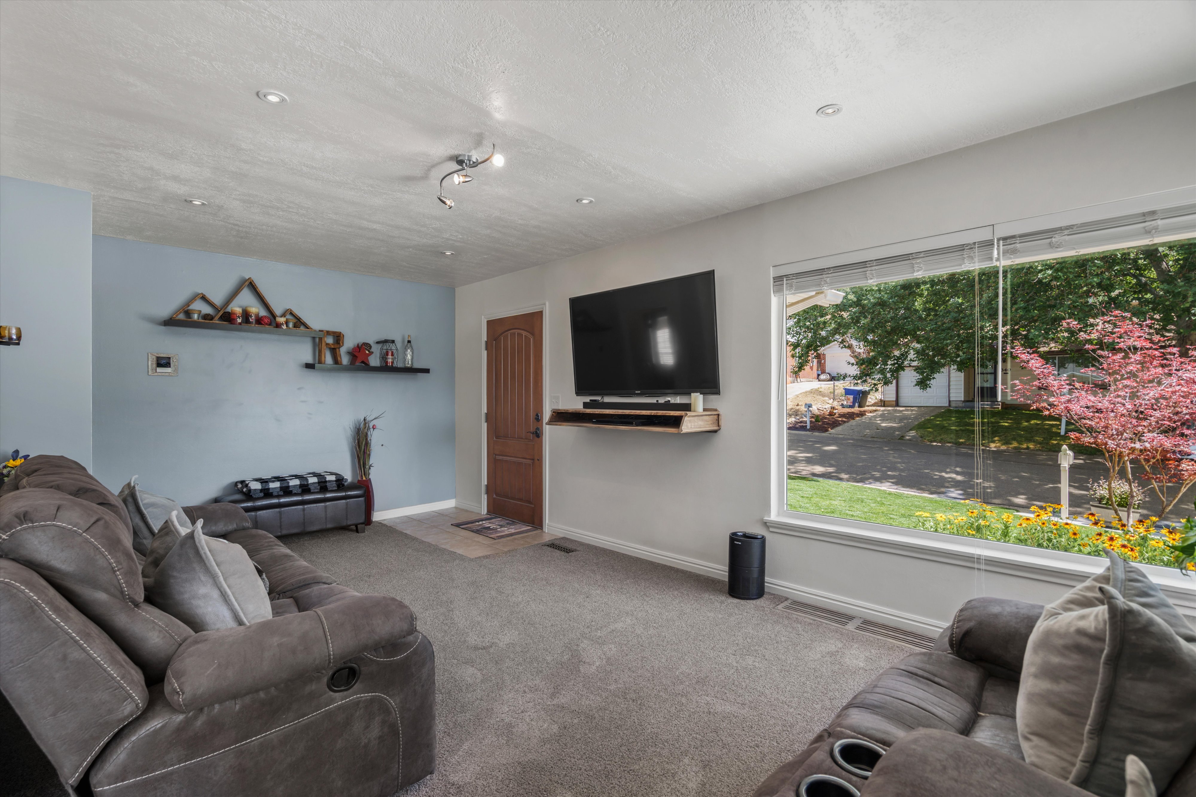 Carpeted living space featuring a large picture window, recessed lighting, and a paneled entry door