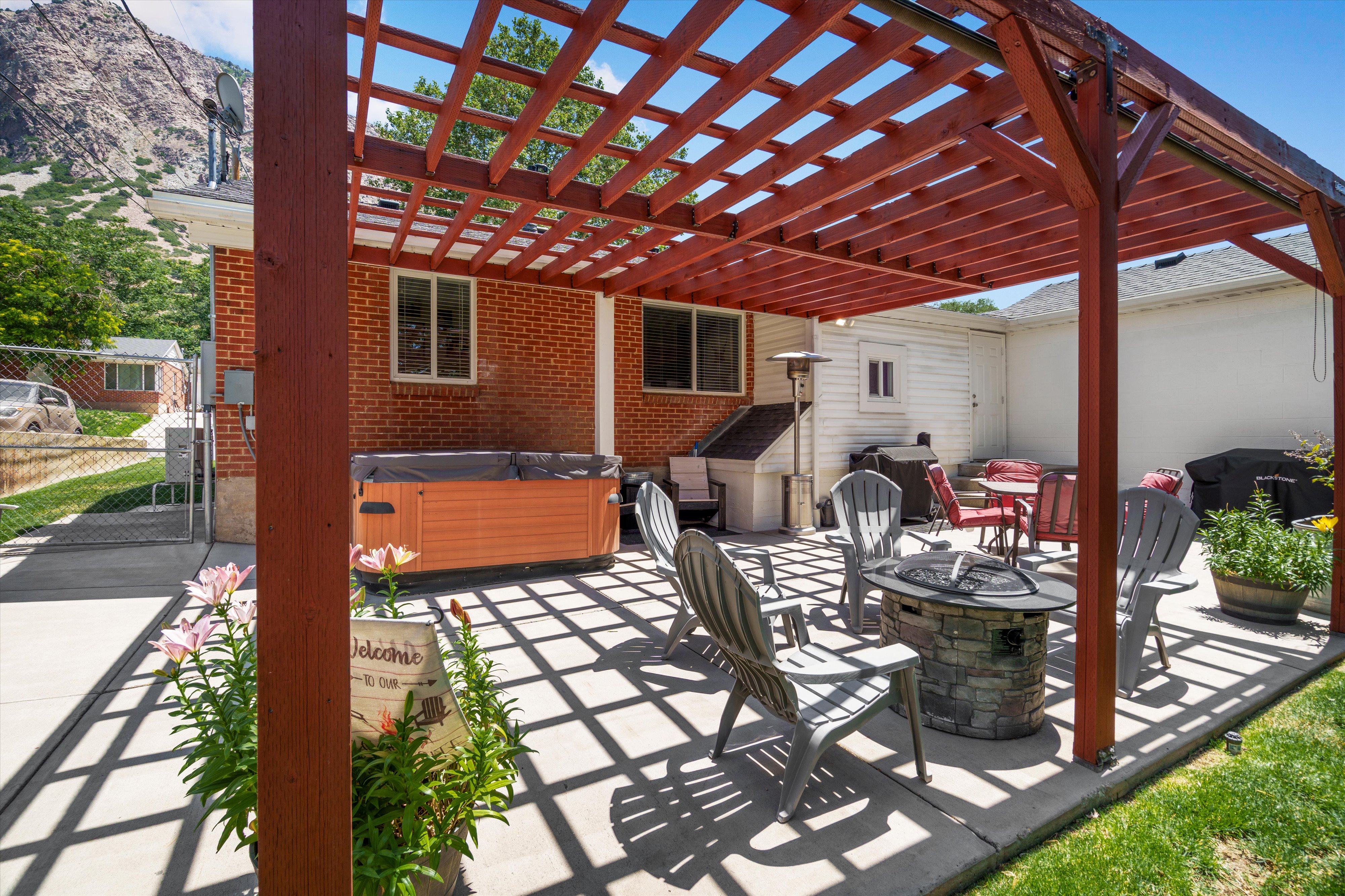 Expansive concrete patio with a red wood pergola providing dappled sunlight