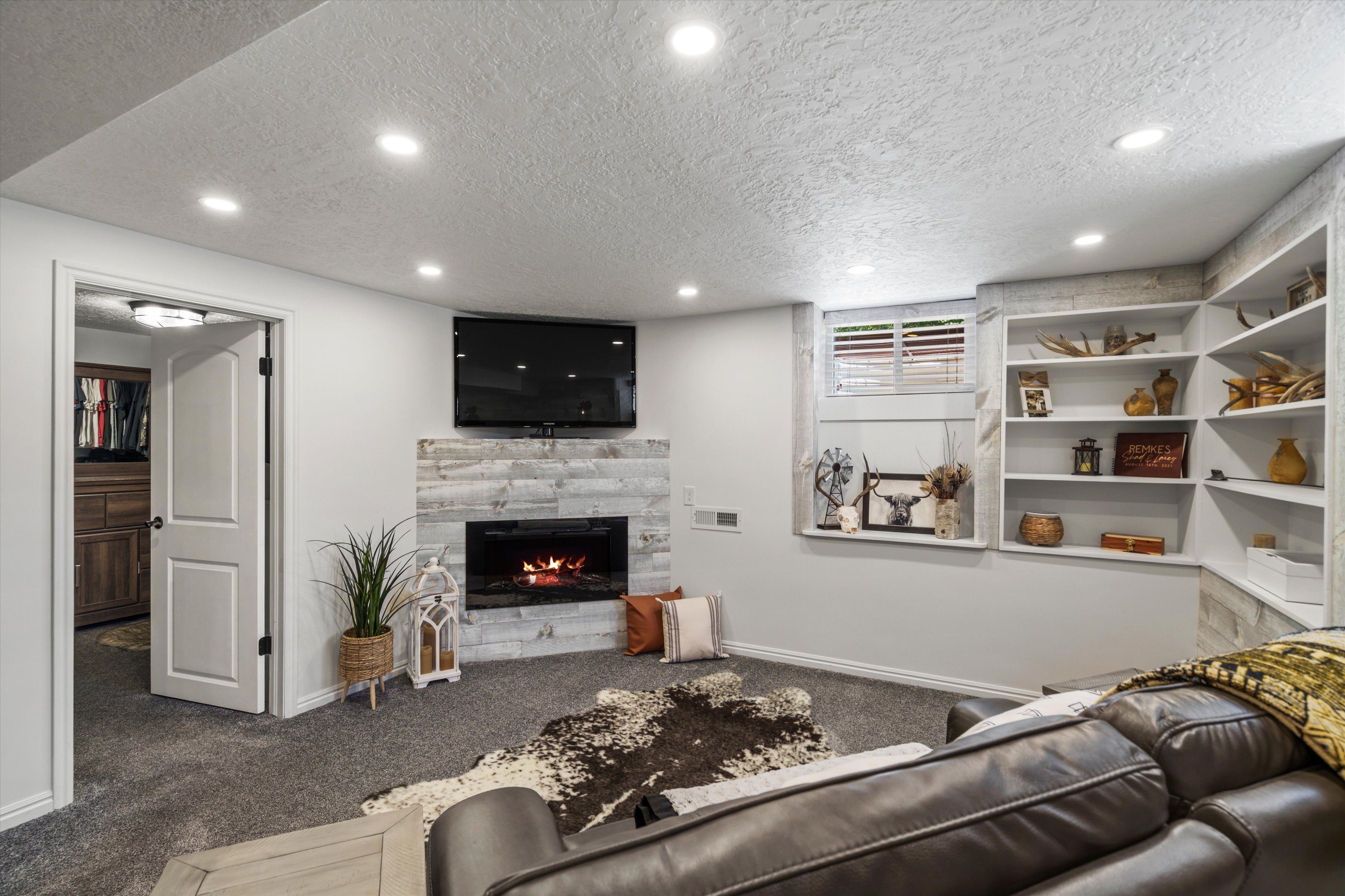 Flexible living space featuring a built-in fireplace with a stacked stone-finish surround, recessed lighting, and built-in shelving. Currently used as primary bedroom.