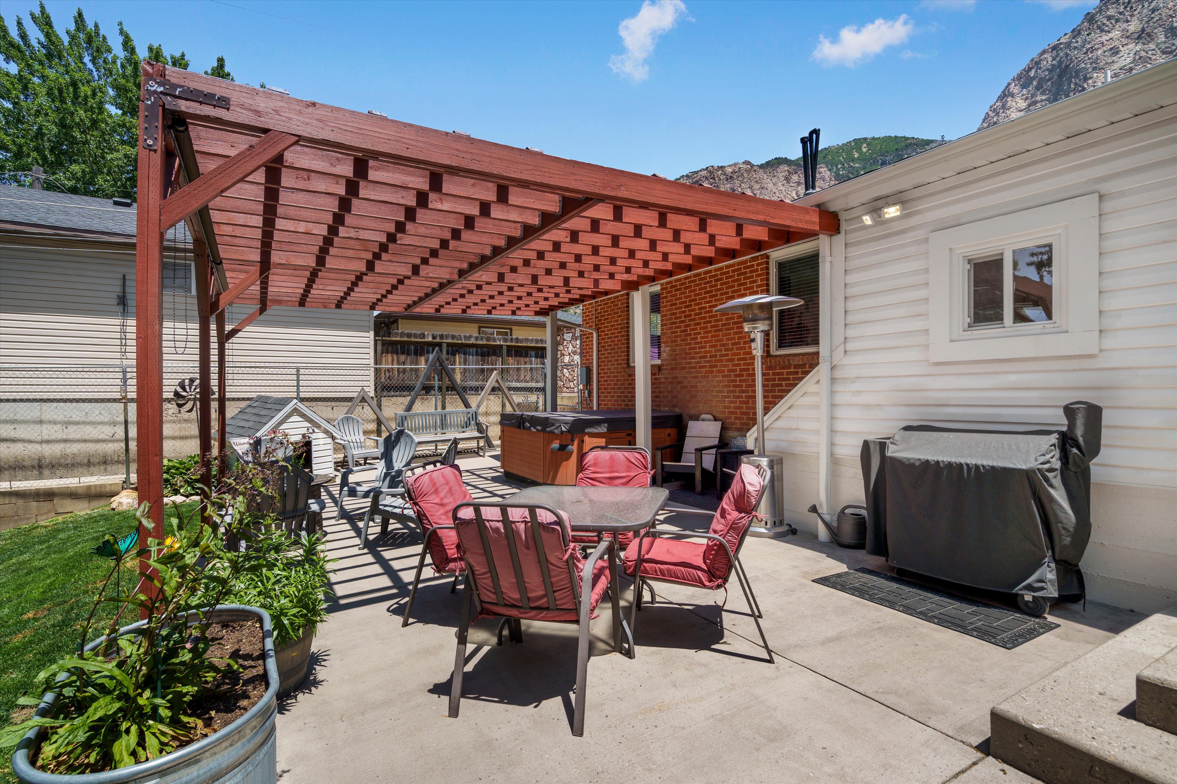 Expansive concrete patio featuring a wood pergola and partial brick exterior