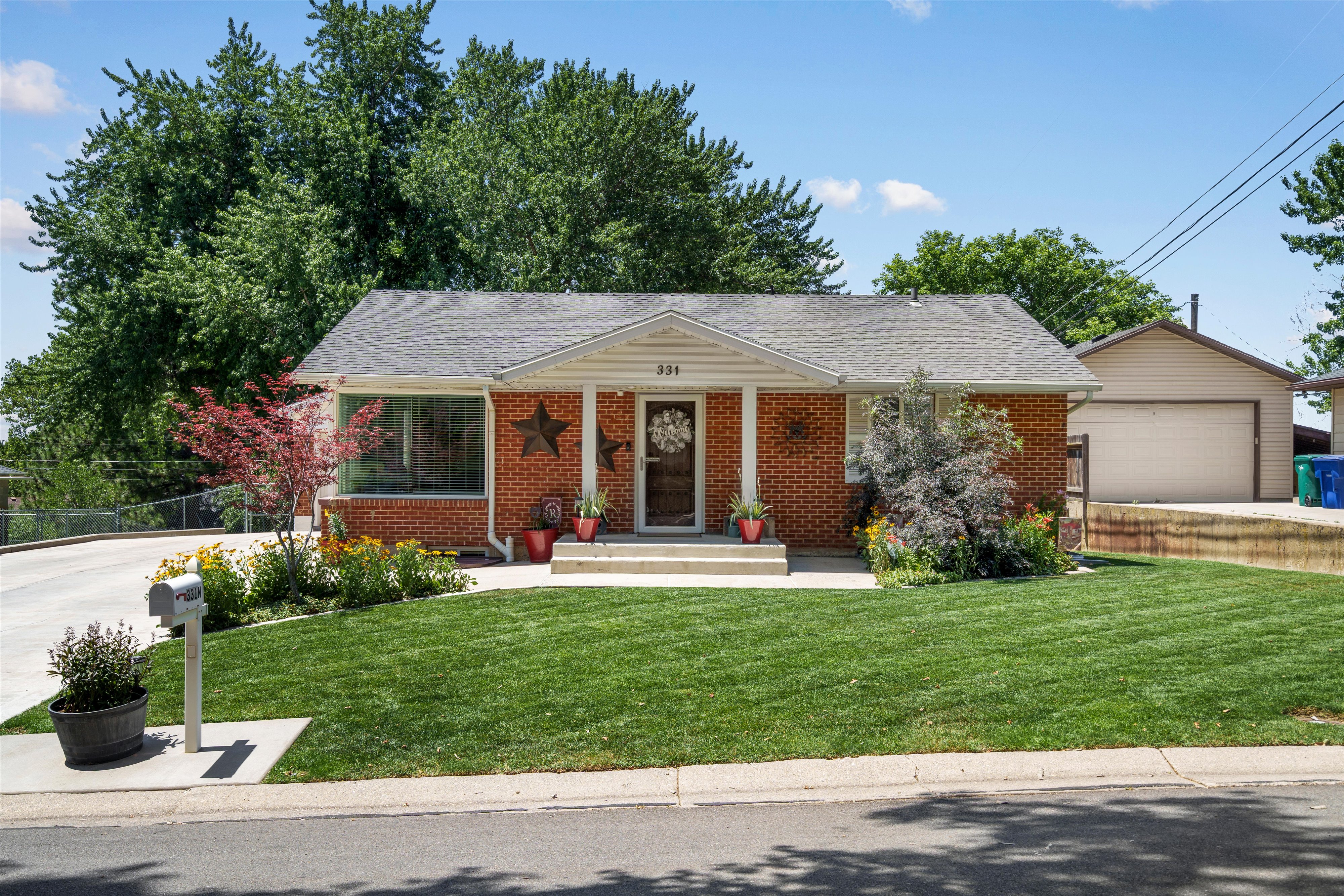 Brick exterior featuring a covered porch entry, a concrete driveway, and a detached garage