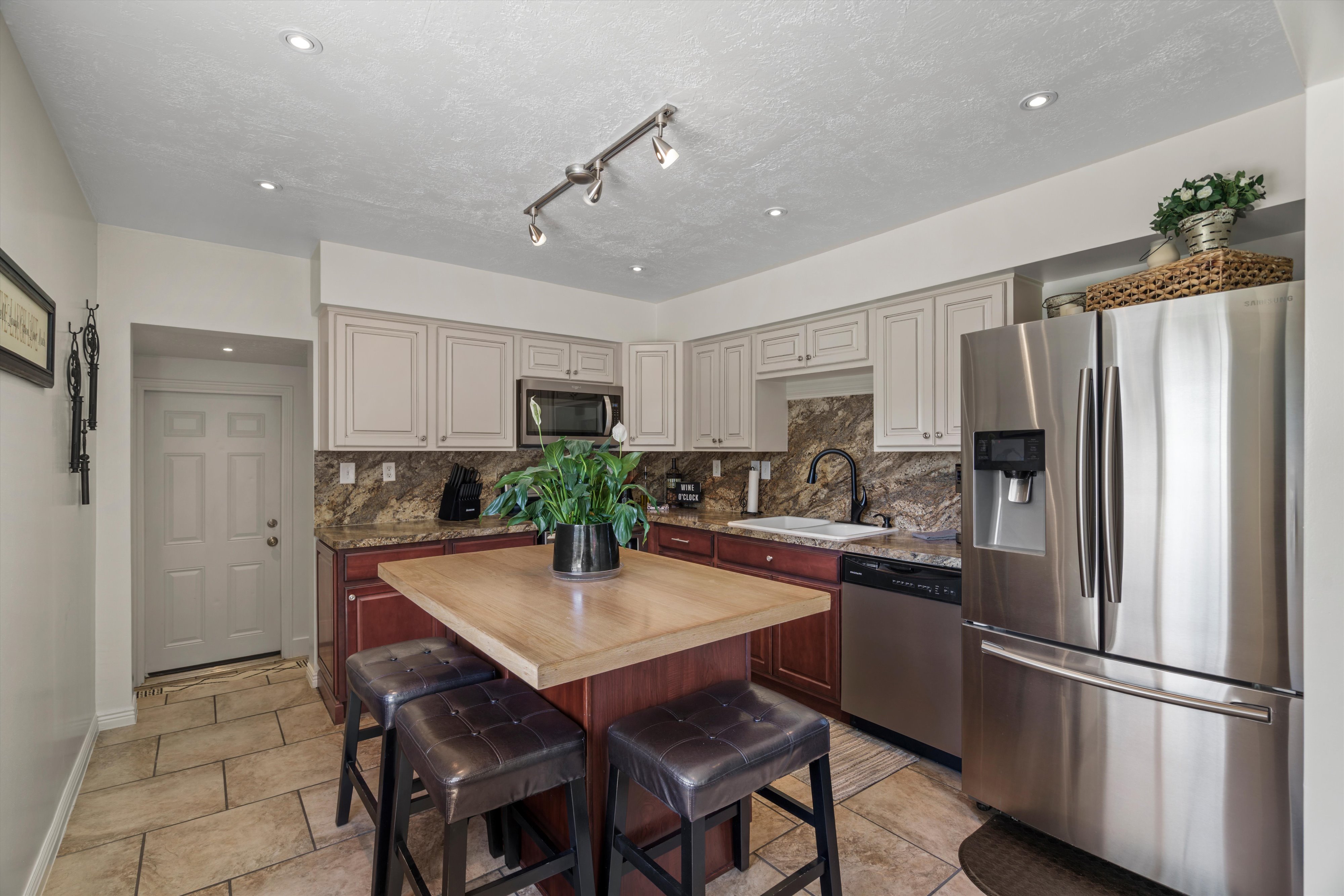 Kitchen featuring a central island with seating, two-tone cabinetry, stainless steel appliances, and backsplash
