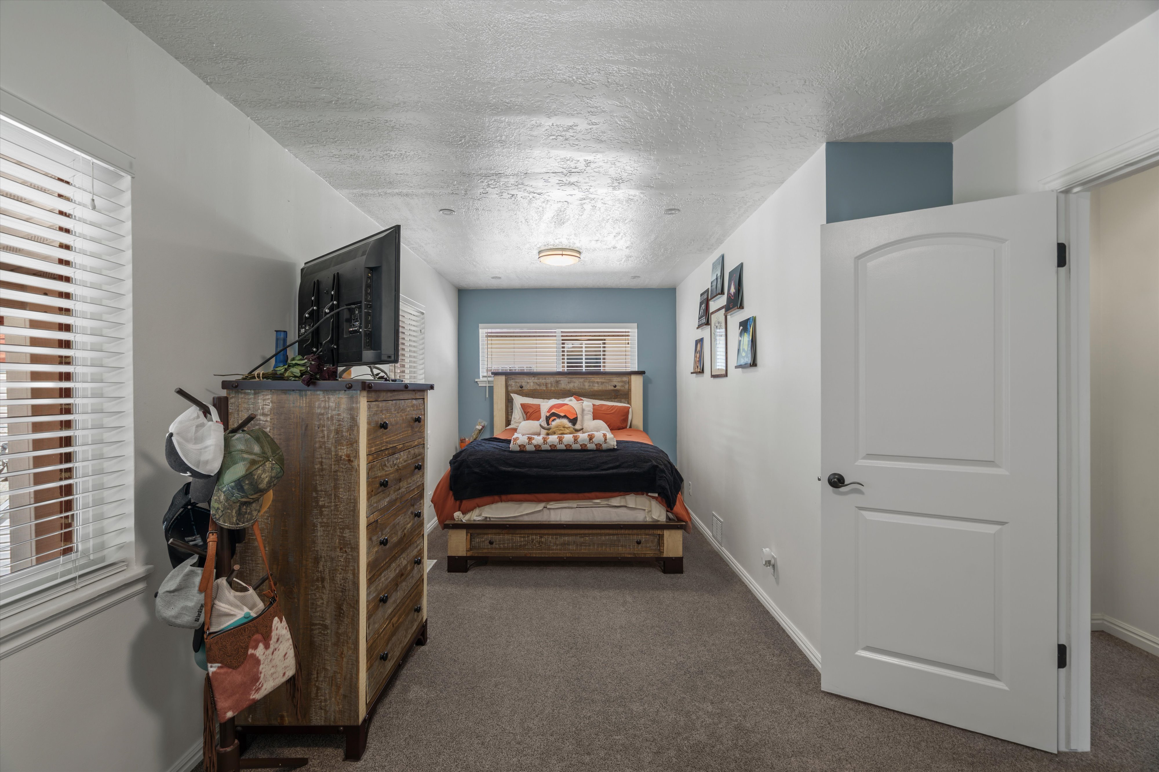 Recessed lighting illuminates this room featuring white walls and a blue accent wall