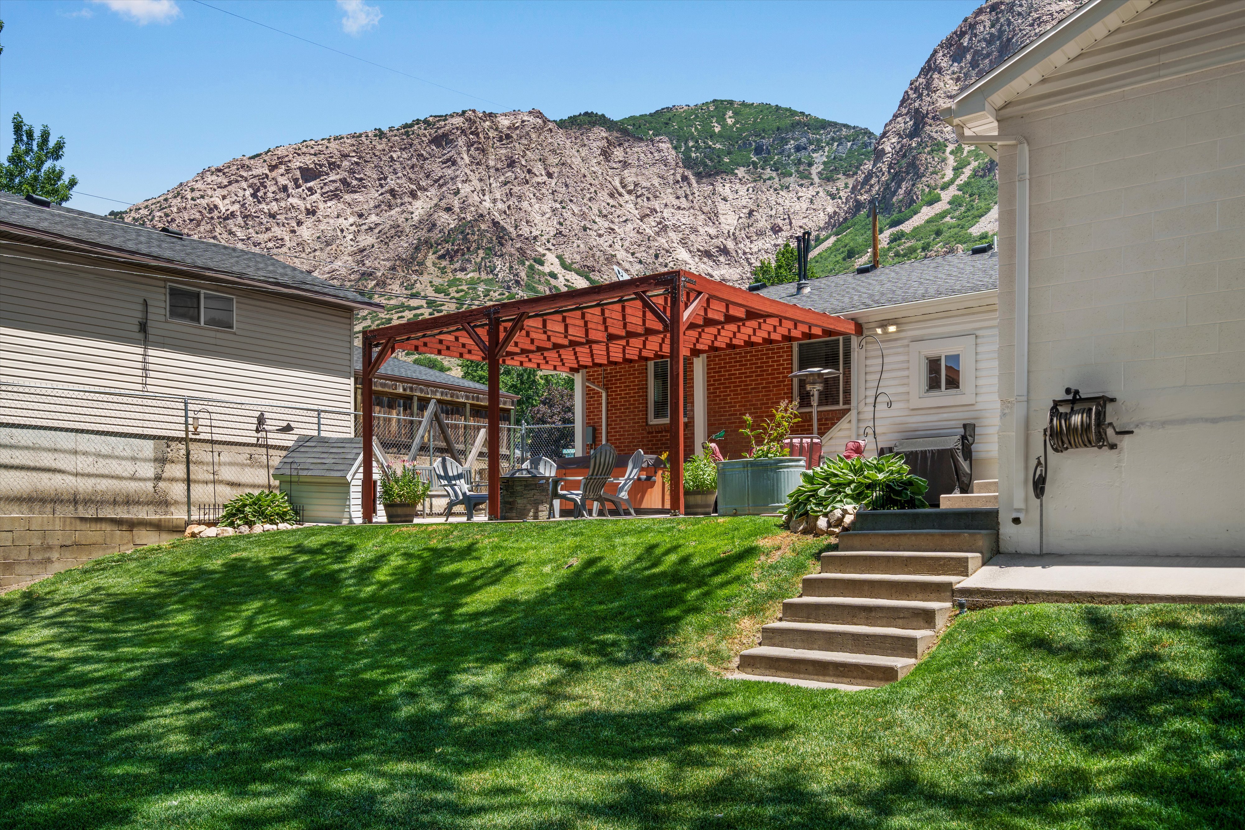 Expansive terraced backyard featuring a vibrant green lawn, concrete steps, and a patio area