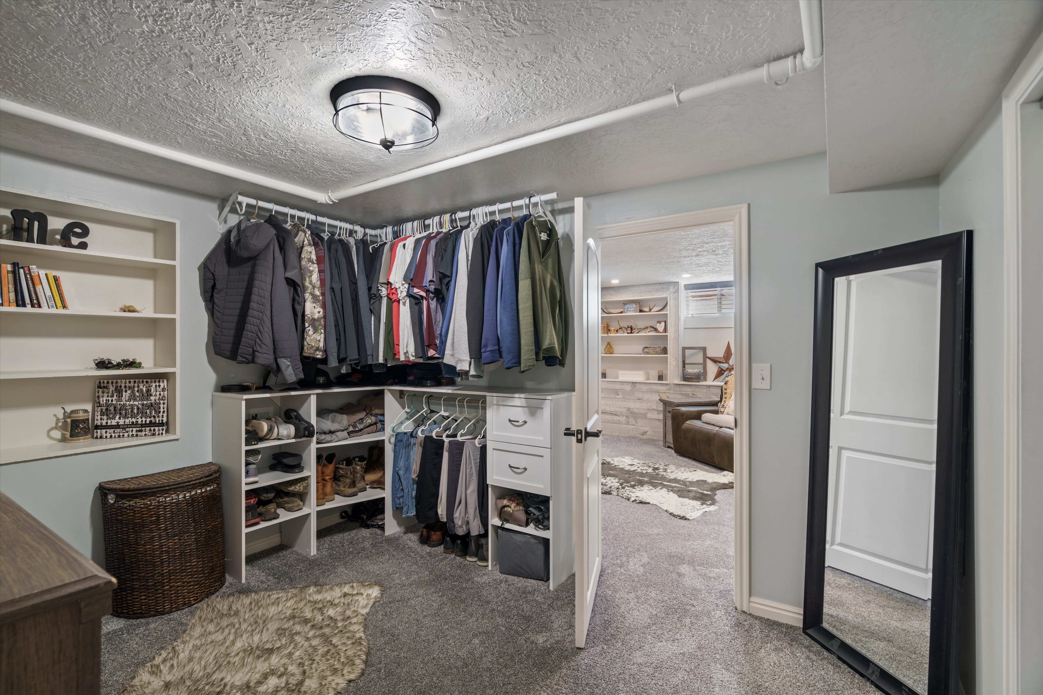 Bedroom converted to walk-in closet featuring built-in shelving, hanging rods, and drawers connected to primary bedroom/family room flex space