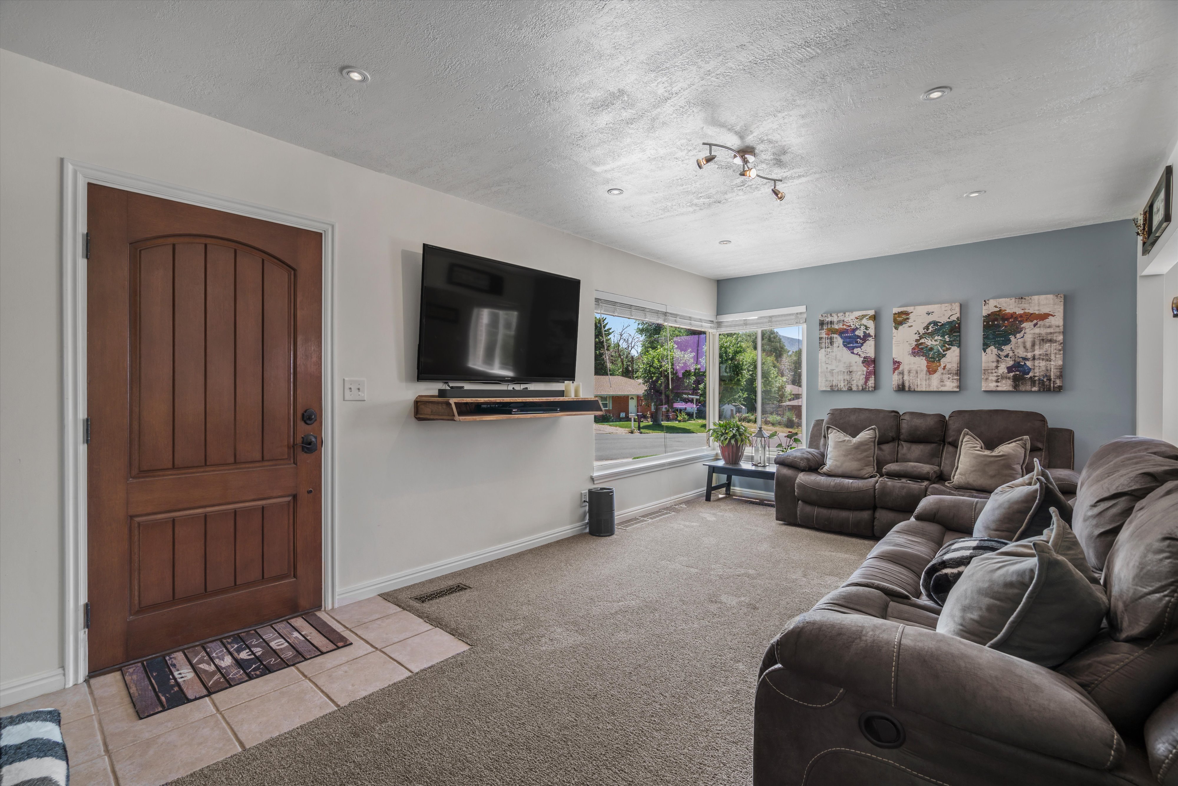 Living area featuring a warm wood entry door, tile flooring, recessed lighting, and expansive windows