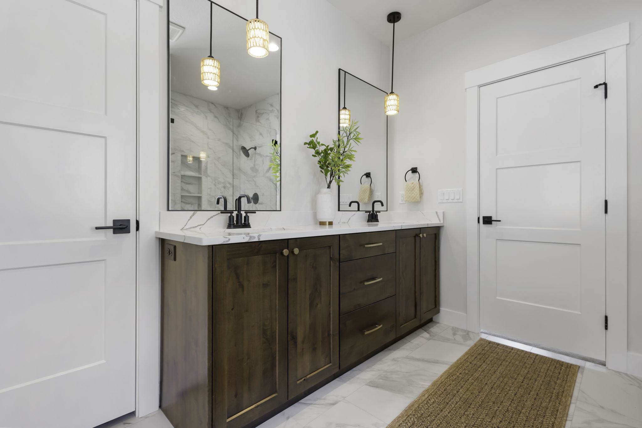 Dual vanity with dark wood-finish cabinetry, white stone countertops, and black fixtures