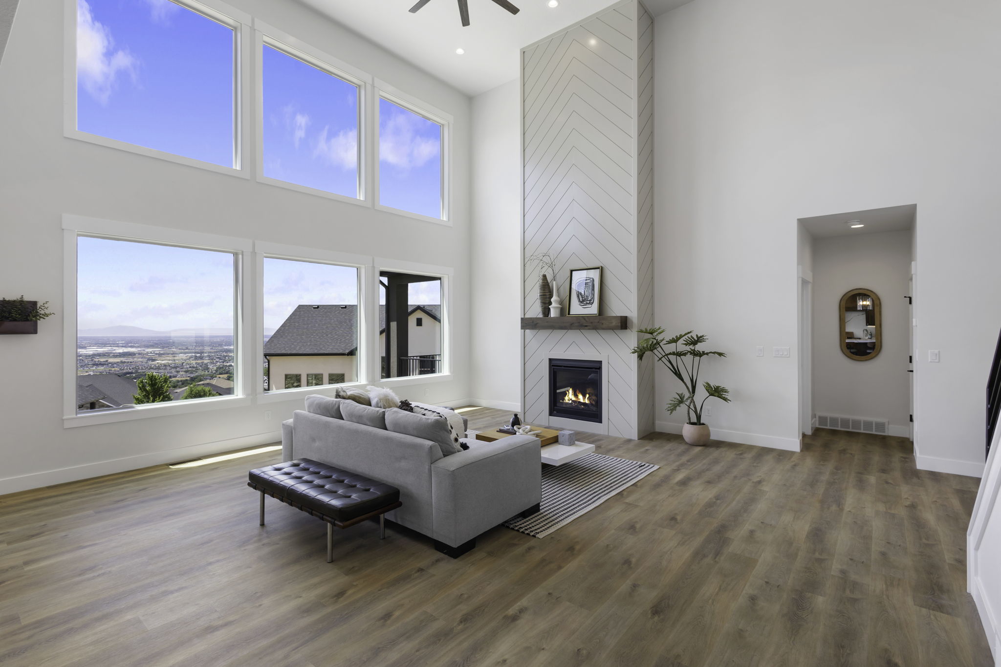 Two-story living area featuring a floor-to-ceiling fireplace with a chevron tile surround and wood mantel