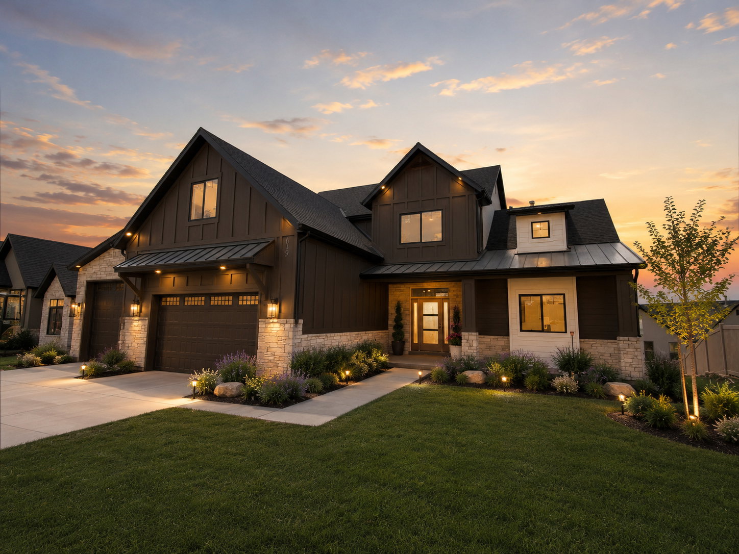 Modern farmhouse exterior featuring dark vertical siding and light-toned stone accents
