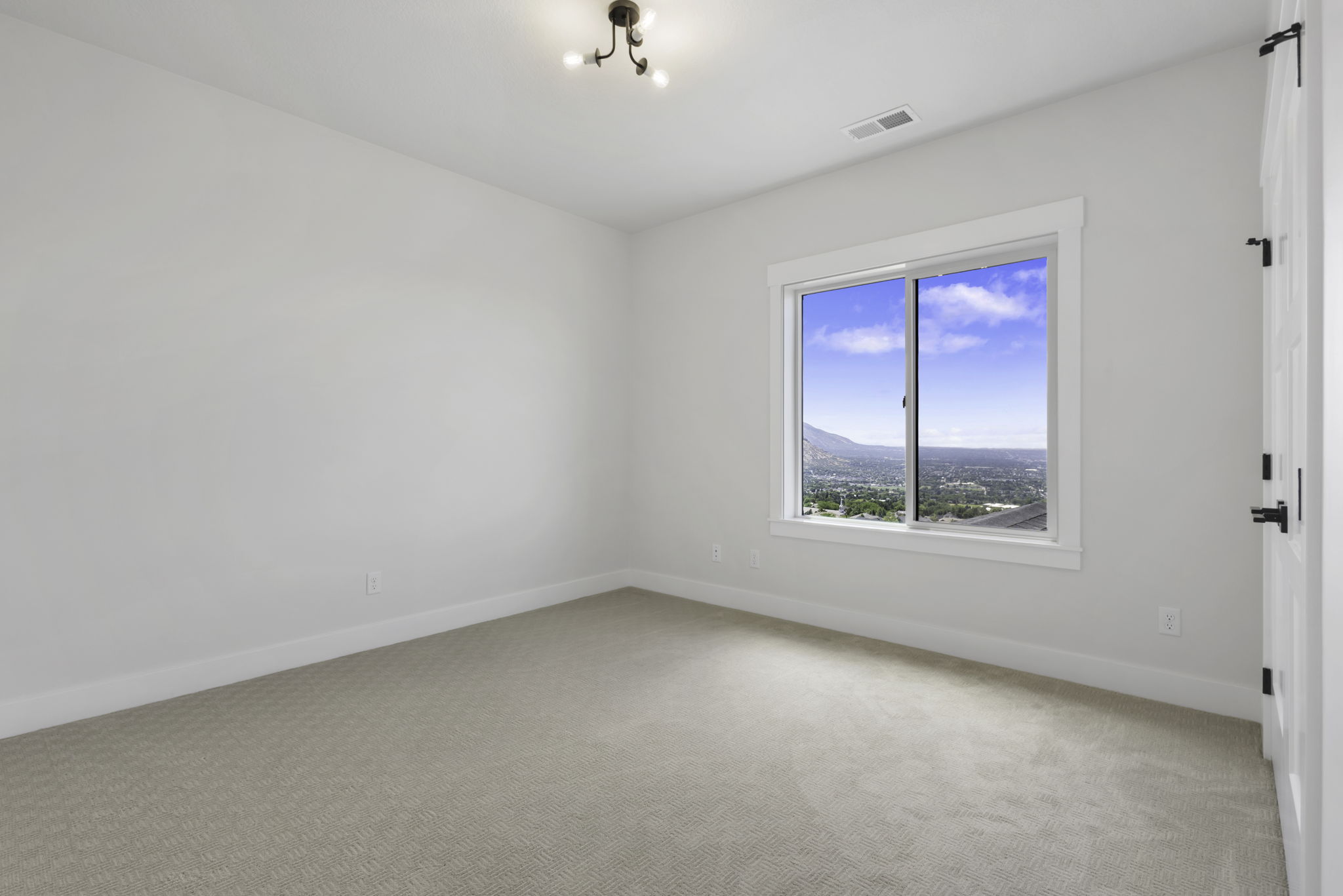 Bright room featuring a large window with mountain and city scenery