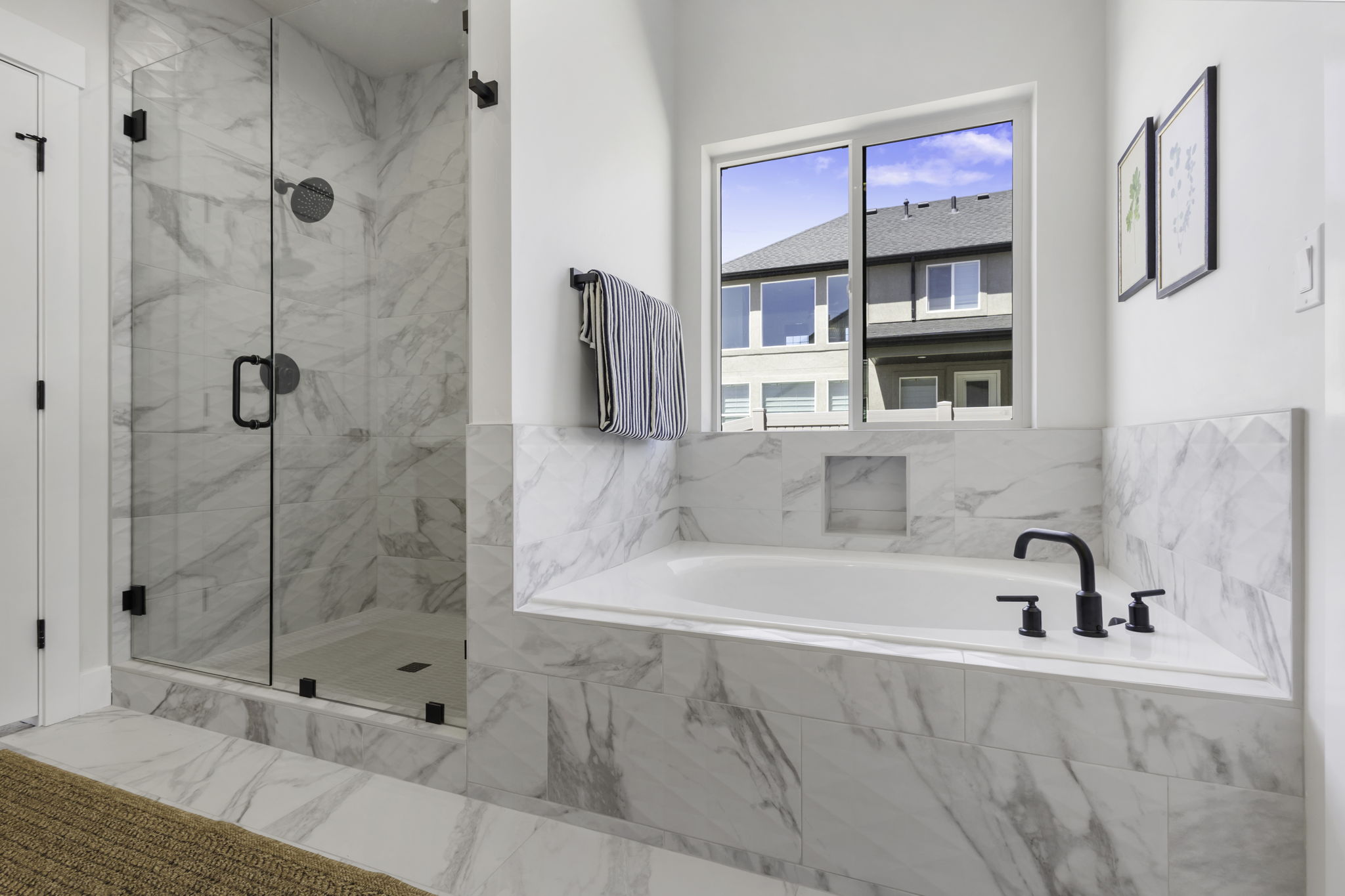 Contemporary bathroom featuring a spacious soaking tub with matte black fixtures, a tiled shower enclosure with clear glass doors, and a built-in recessed shelf