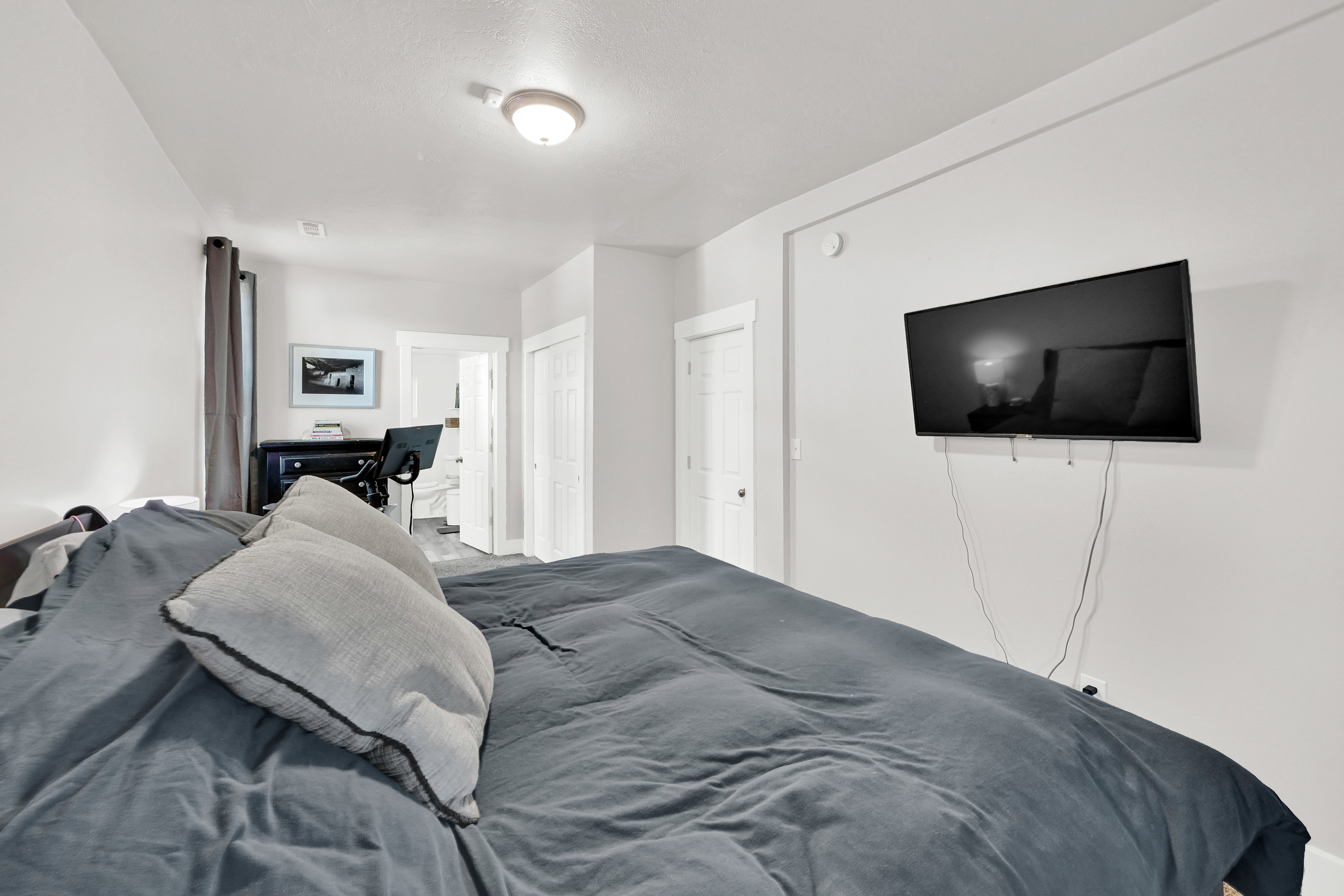 Bedroom featuring a wall-mounted television, neutral wall paint, white trim, and a ceiling-mounted light fixture
