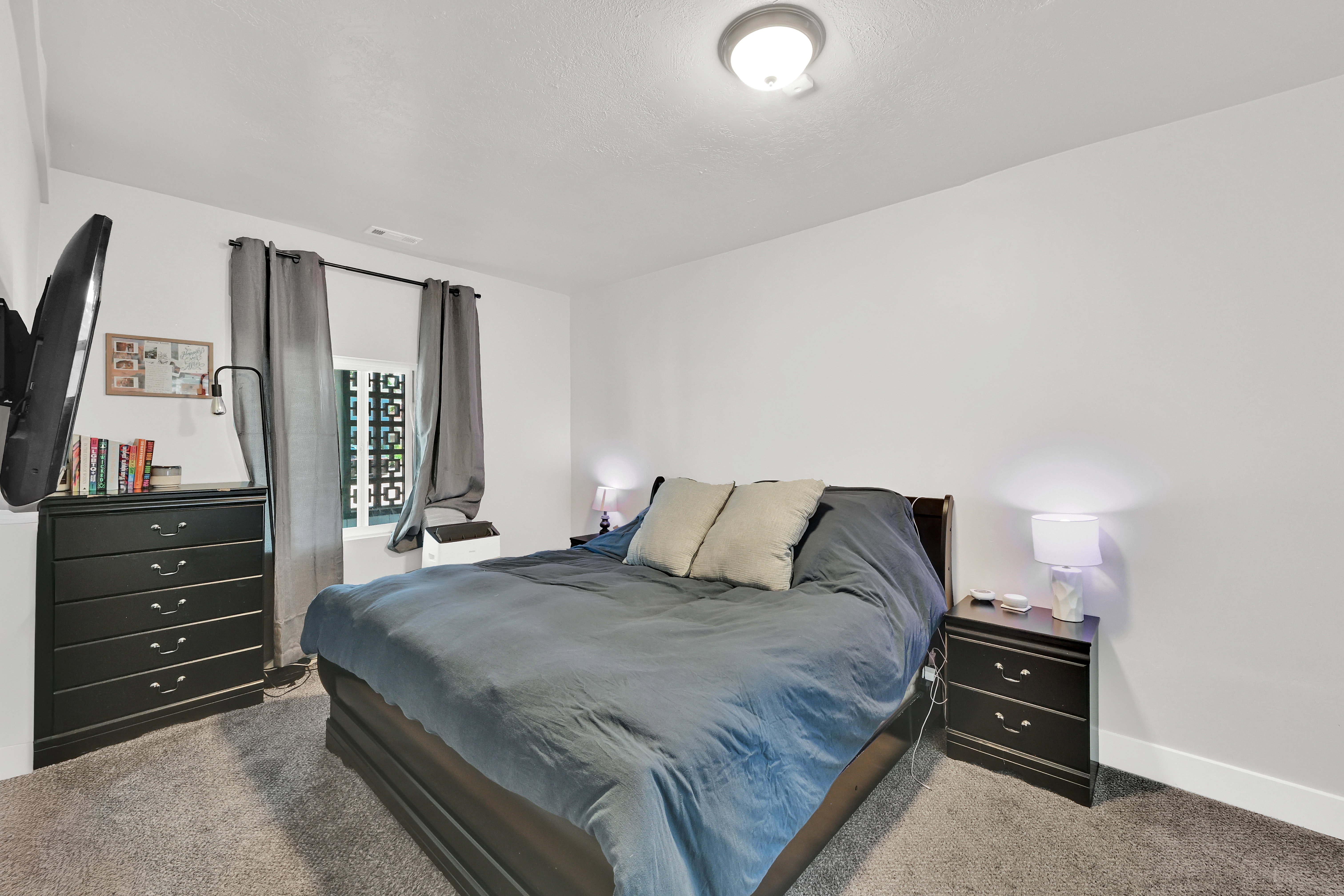 Carpeted room featuring a window with decorative metalwork, white walls, and a ceiling-mounted light fixture