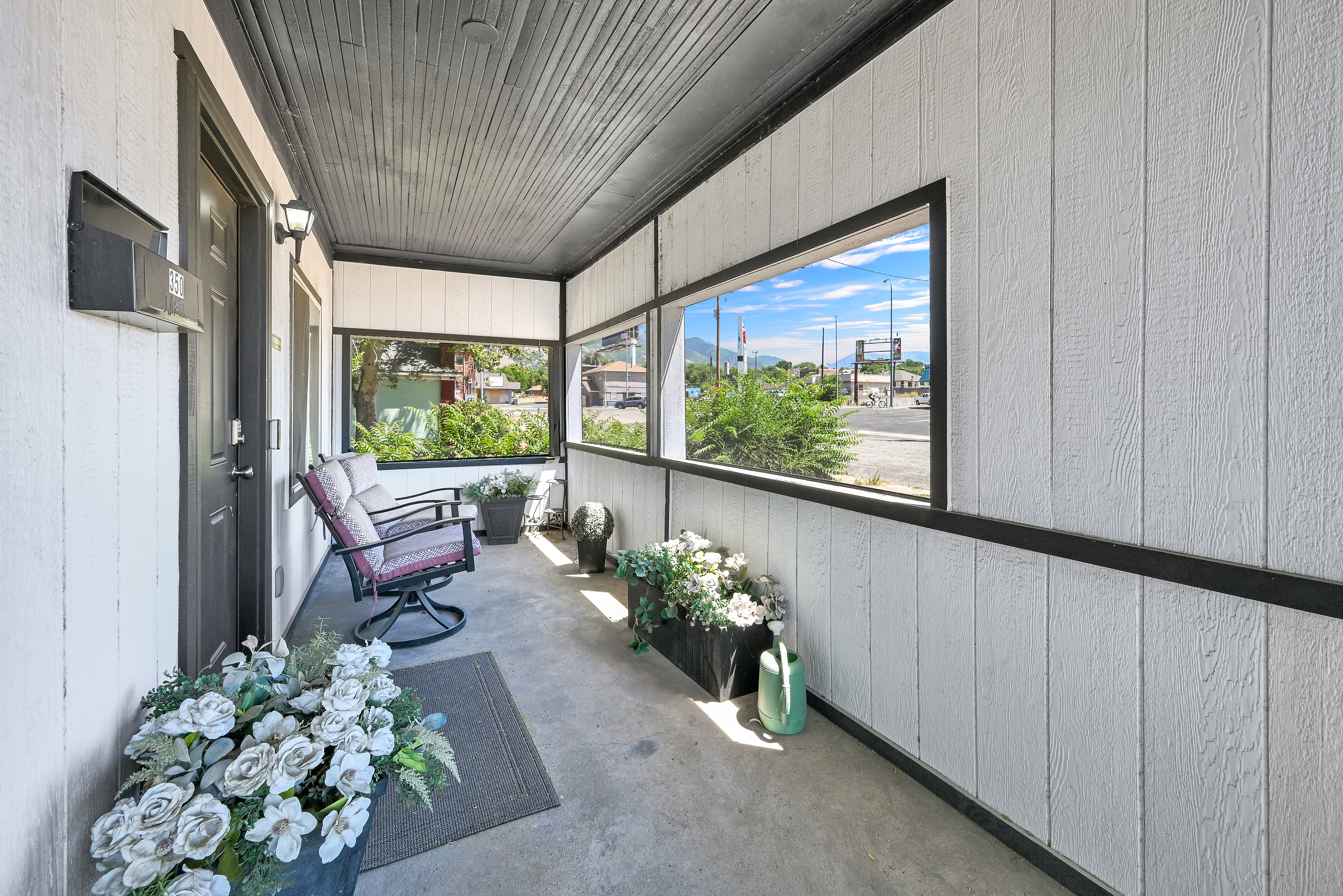Covered porch with white vertical siding and black trim