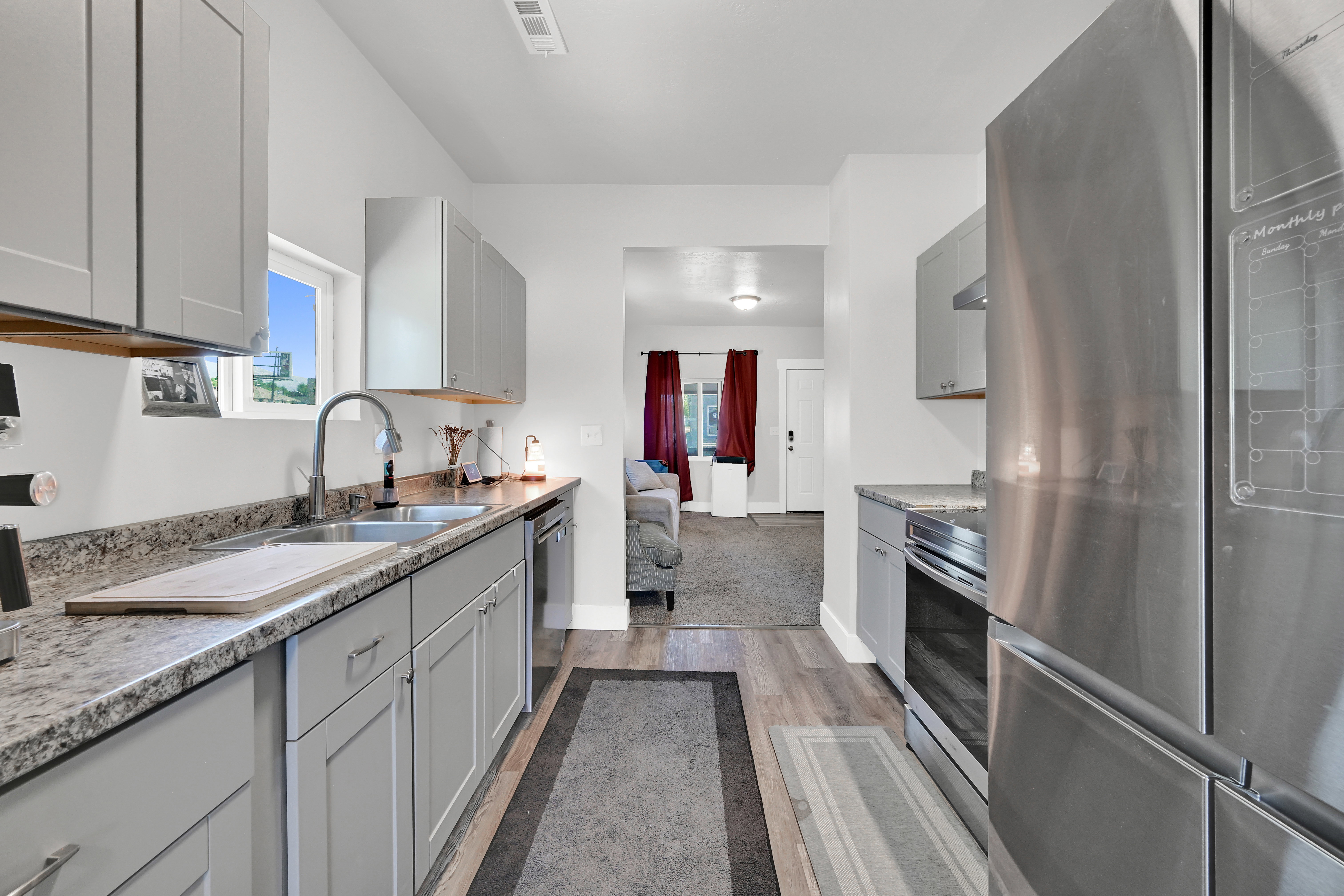 Kitchen featuring light gray cabinetry, a double basin stainless steel sink, and wood-finish flooring
