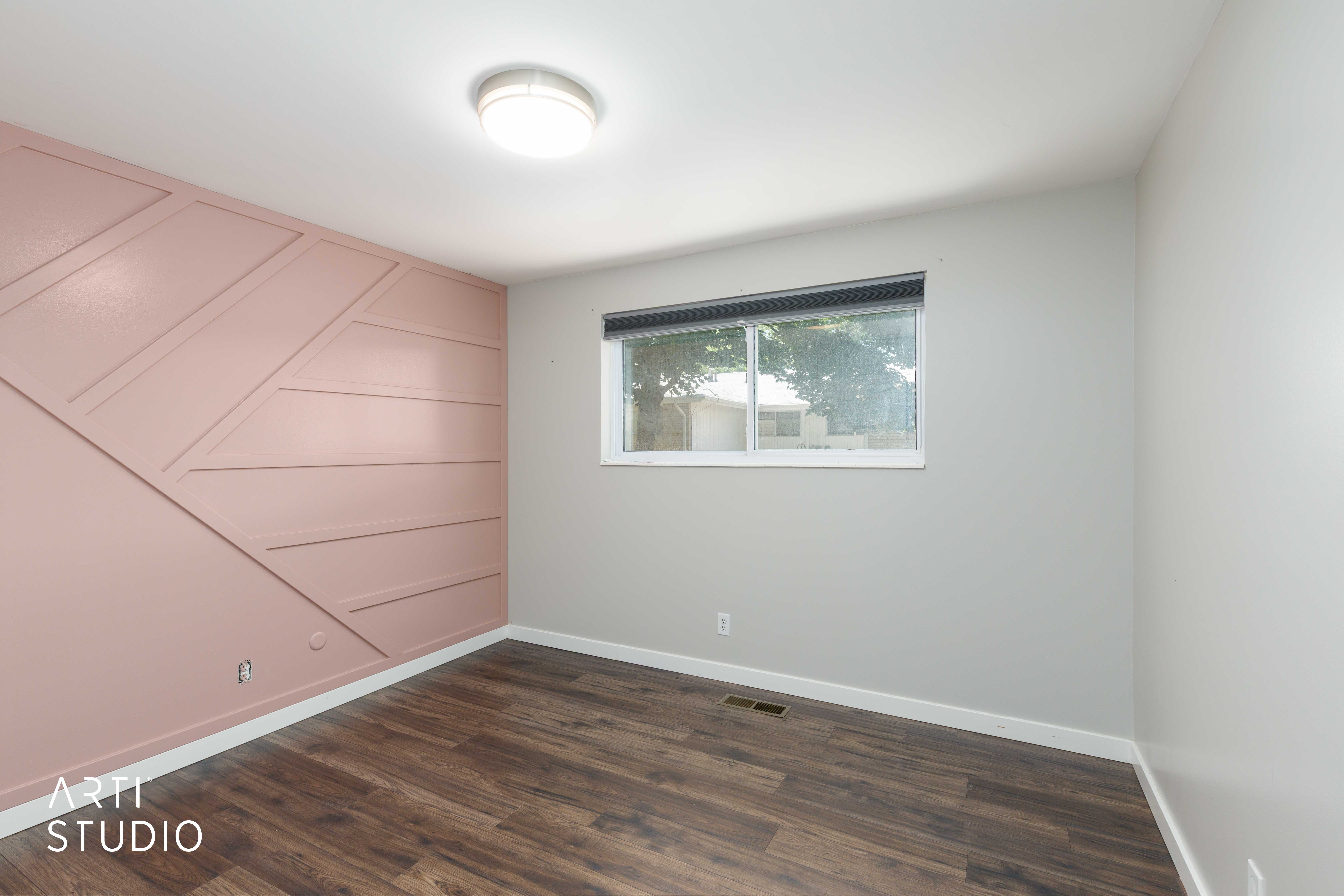 Accent wall featuring geometric paneling, wood-finish flooring, white baseboards, and a flush-mount ceiling light