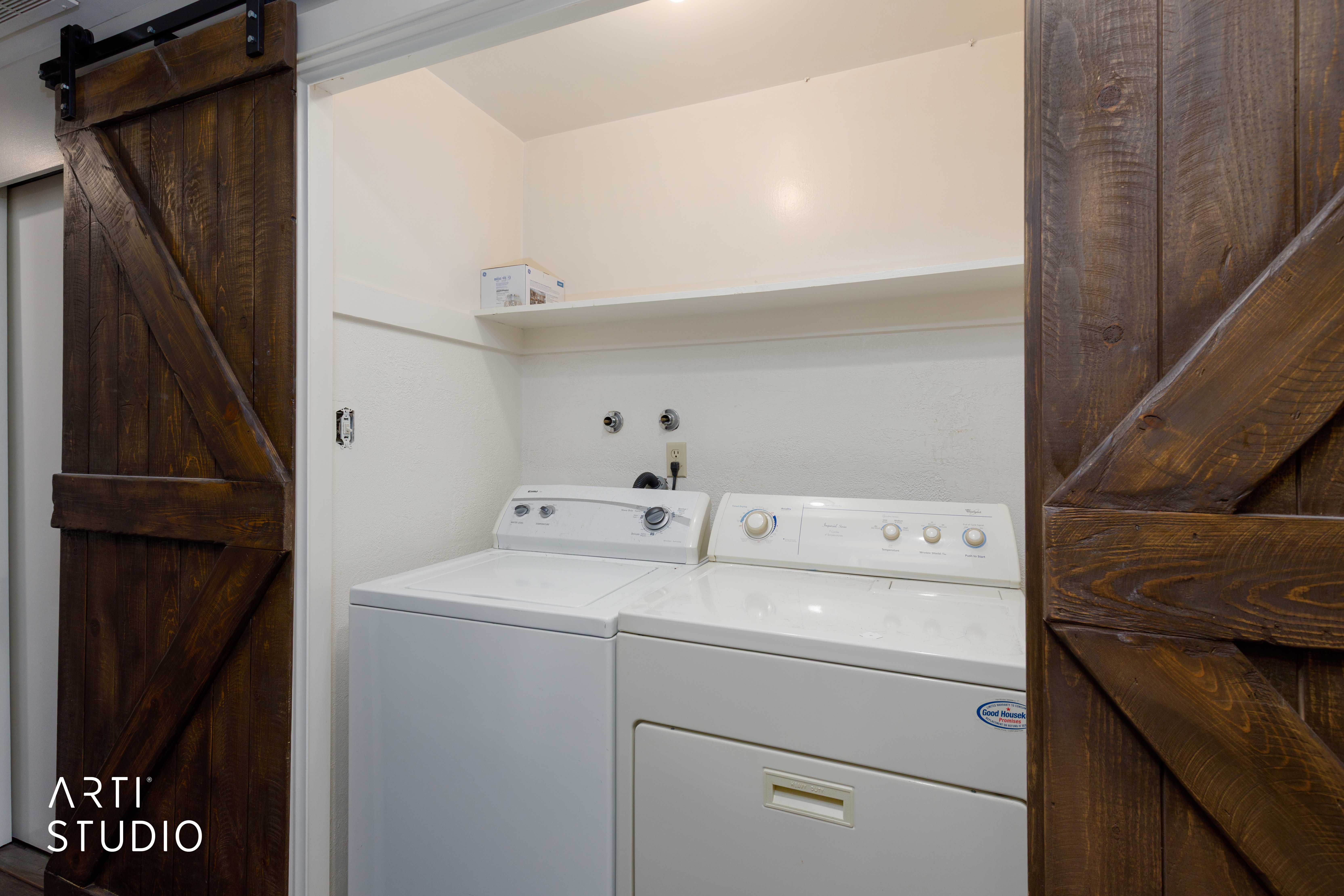 Laundry area featuring a built-in shelf and barn-style sliding wood doors with dark hardware
