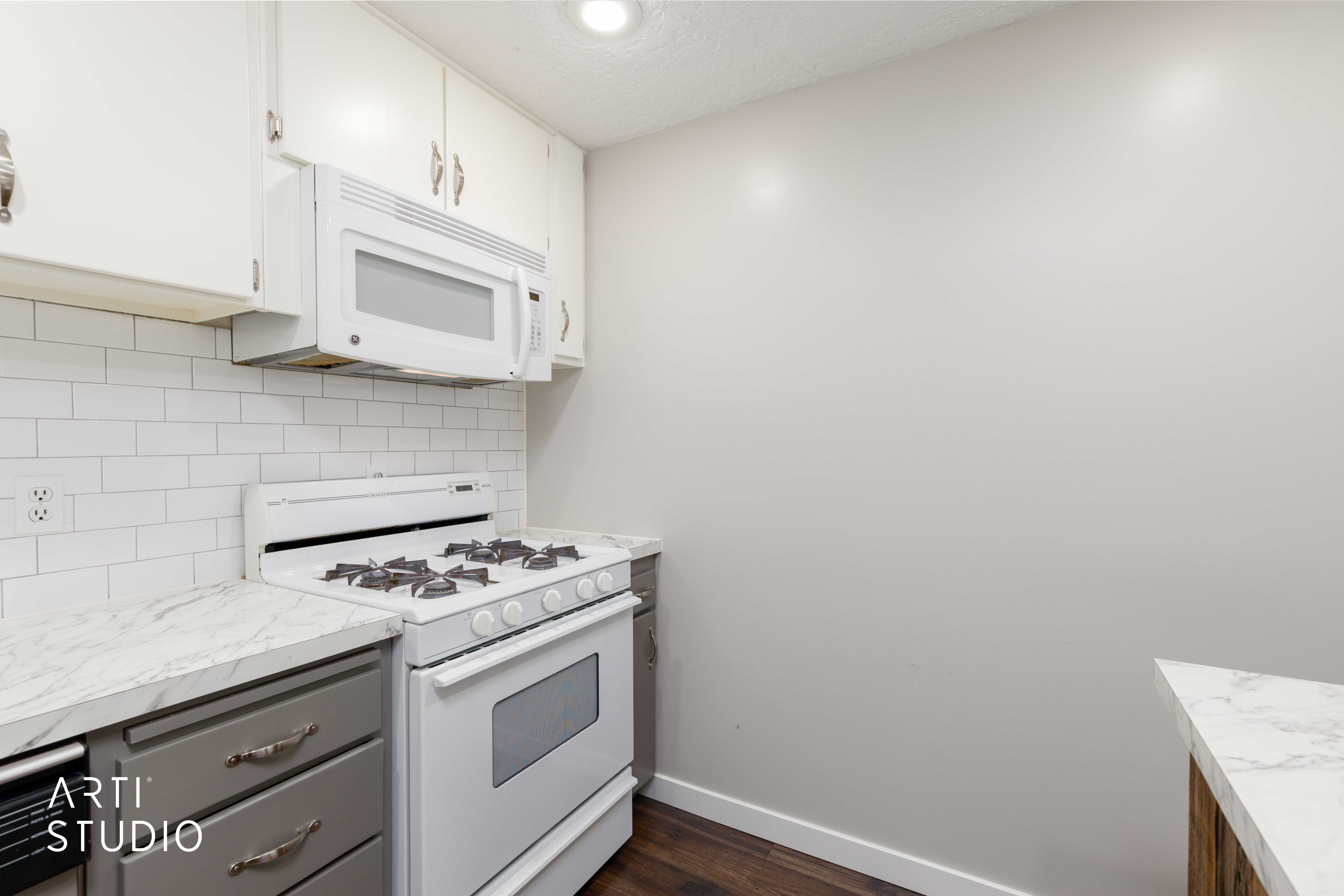 Kitchen featuring white subway tile backsplash, white upper cabinetry, grey lower cabinetry, a white gas range, and a built-in microwave