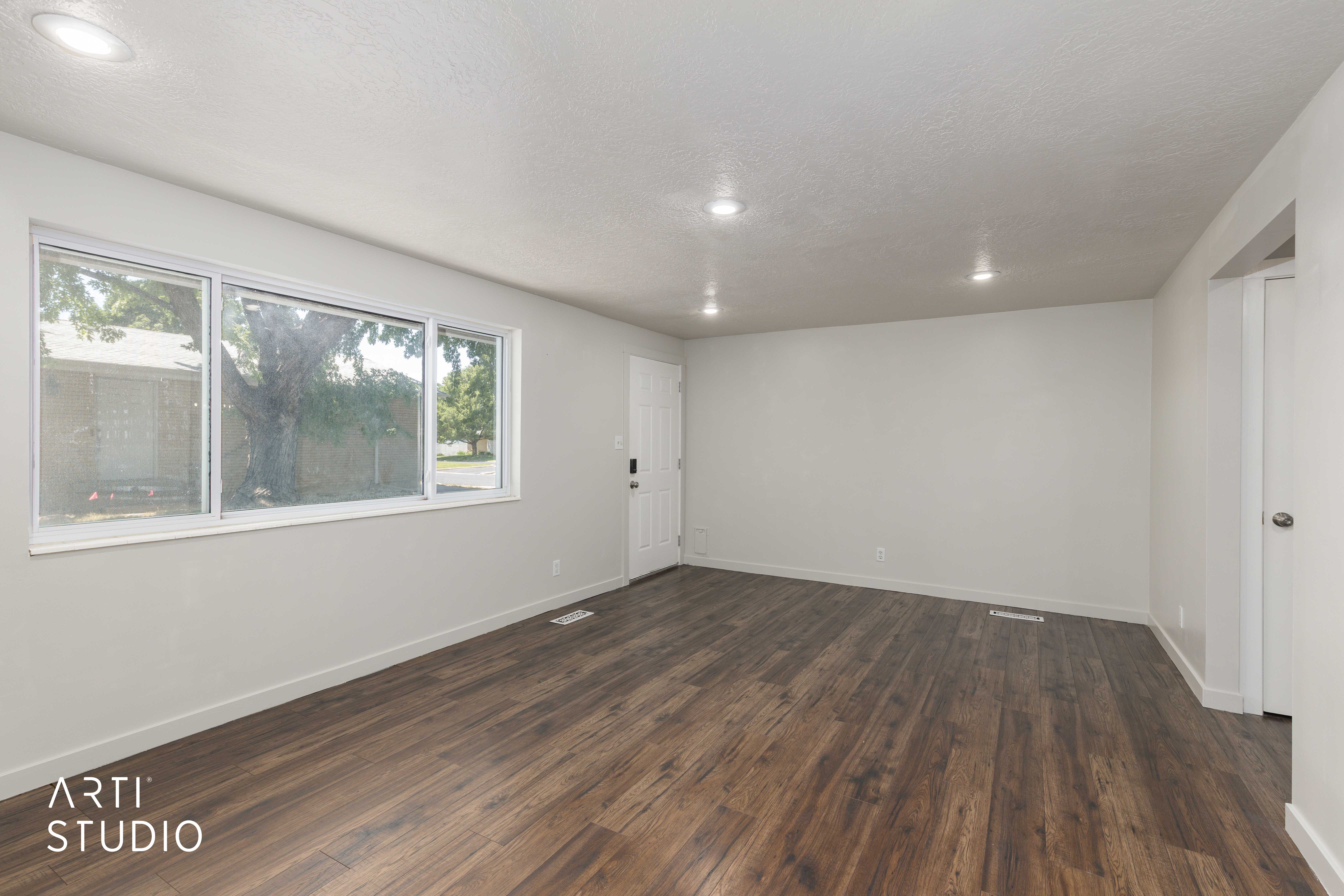 Spacious room featuring wood-finish flooring, recessed lighting, and a large multi-pane window