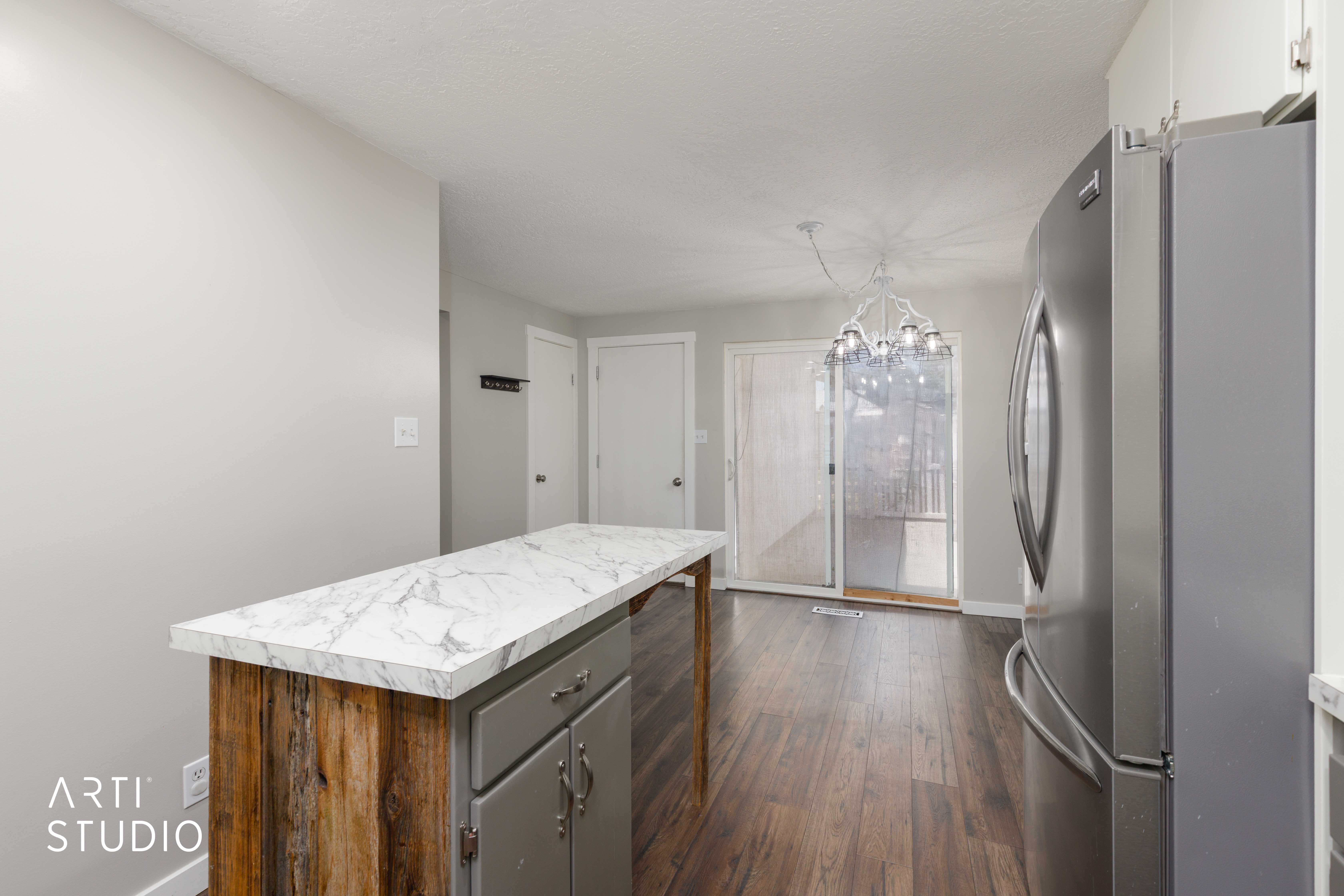 Kitchen featuring a rustic wood and gray island with a marble-finish countertop, stainless steel refrigerator, and wood-finish flooring