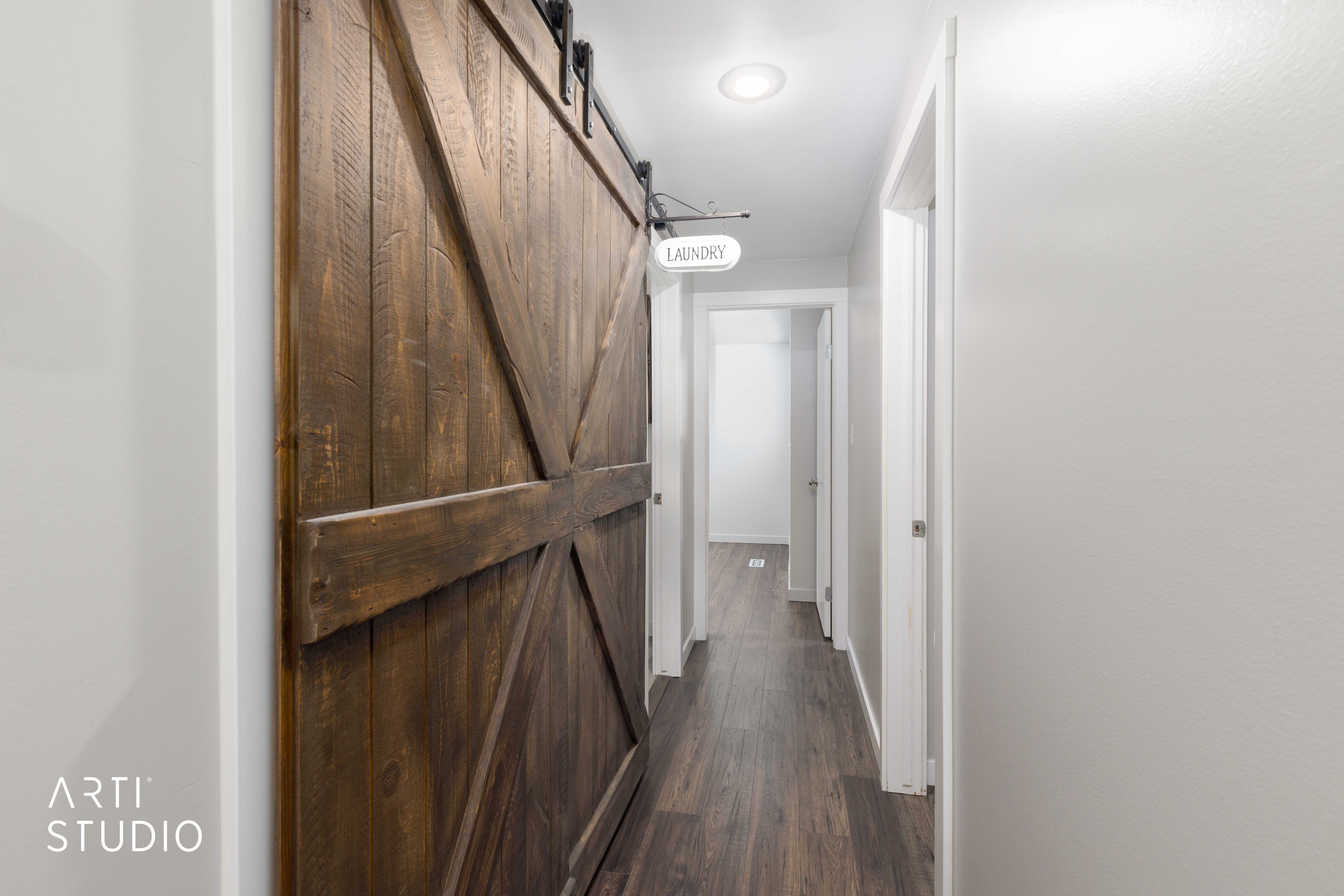 Barn-style sliding door with dark wood finish, dark hardware, and a white laundry sign