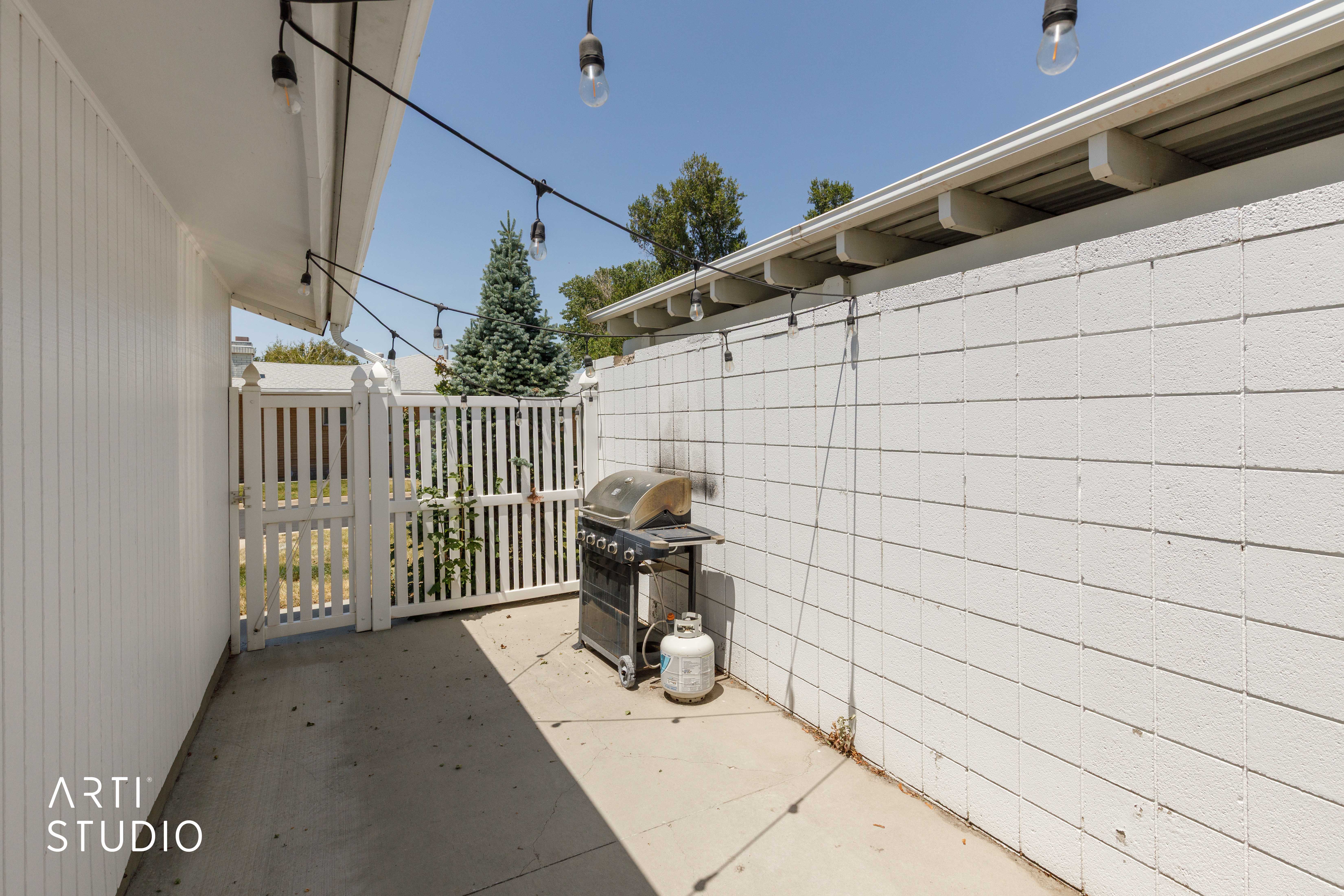 Patio area featuring a concrete slab, white vertical siding, and a white block wall