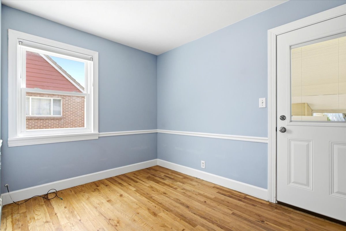 Room featuring wood-finish flooring, light blue walls with white chair rail molding, and a white trim window