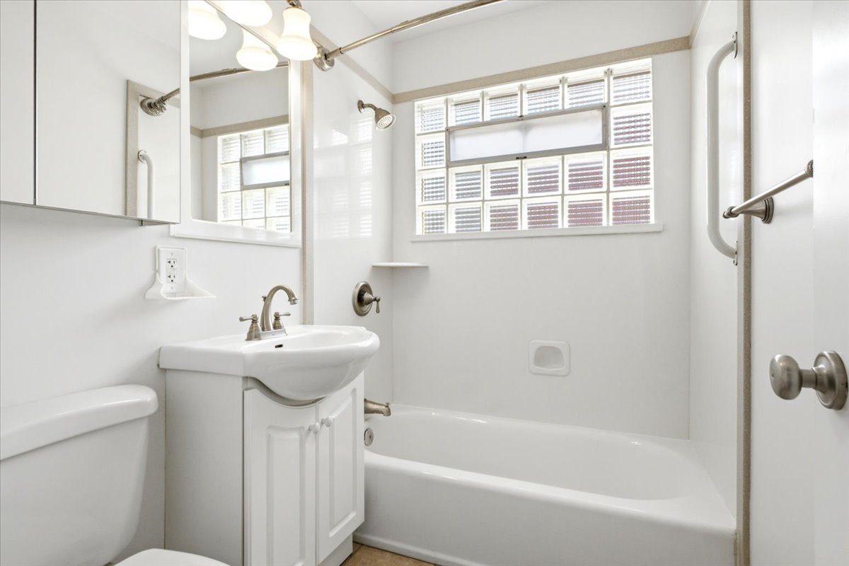 Bathroom featuring a white vanity with integrated sink, brushed nickel faucet, and coordinating cabinet hardware